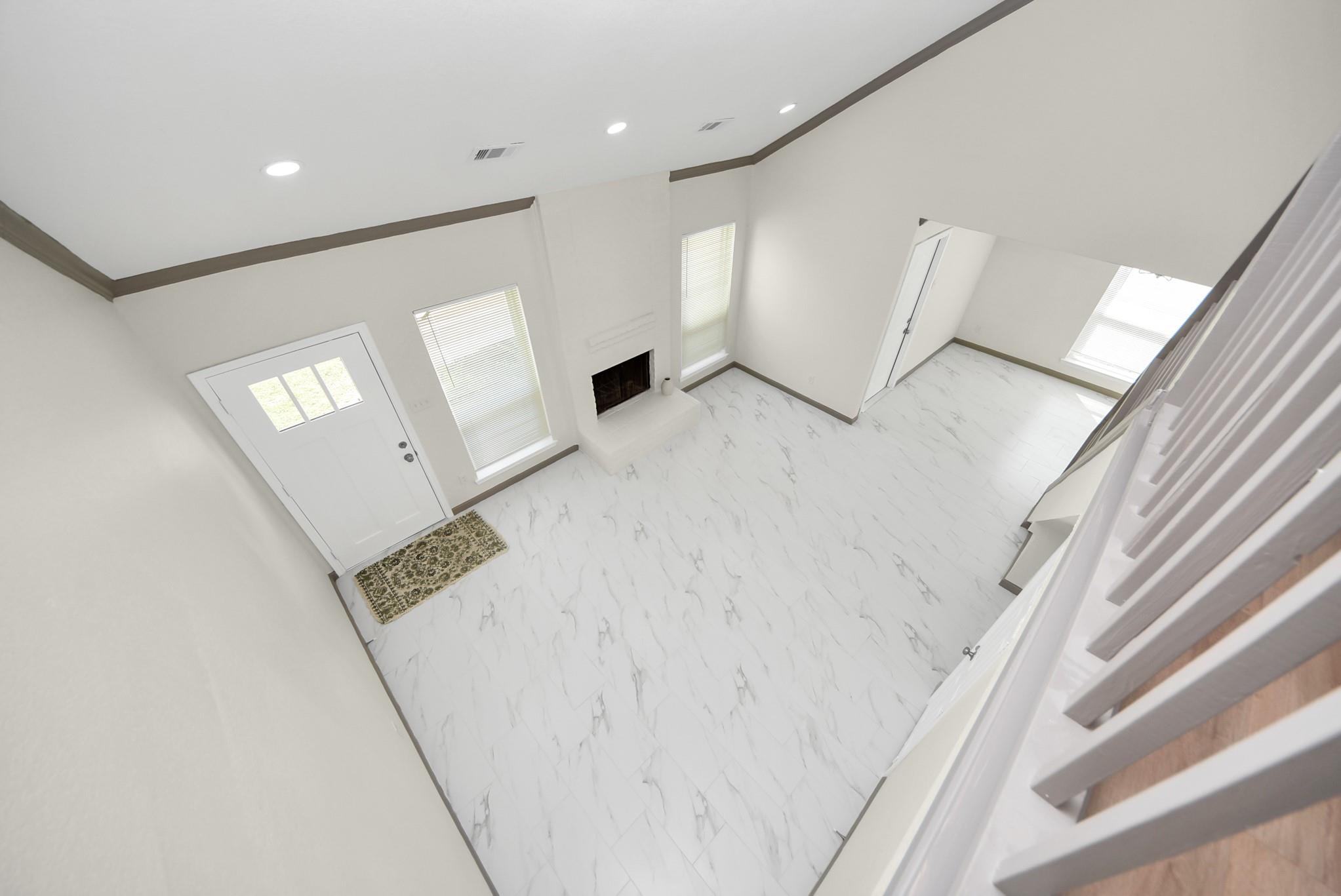 Vacant living room with marble-look tile floors, a fireplace, and high ceilings.