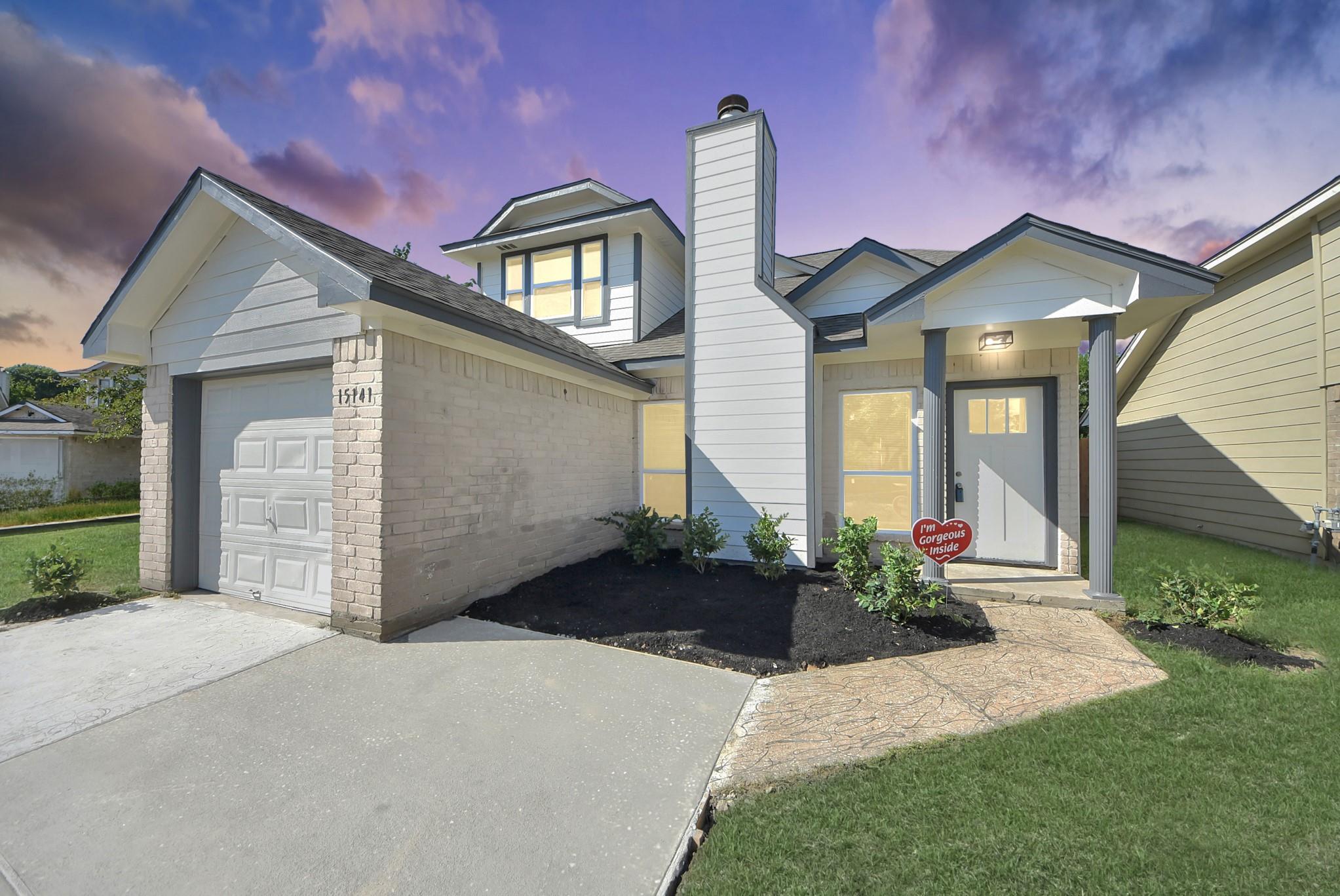 House exterior with a garage, covered entry, brick facade, and landscaped front yard.