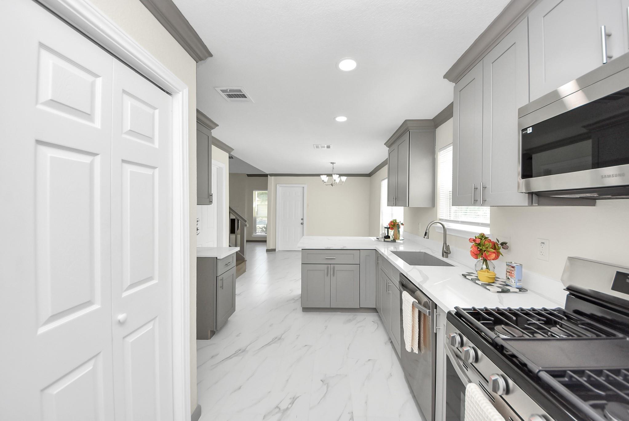 Kitchen with gray cabinets, a white island, and stainless steel appliances.