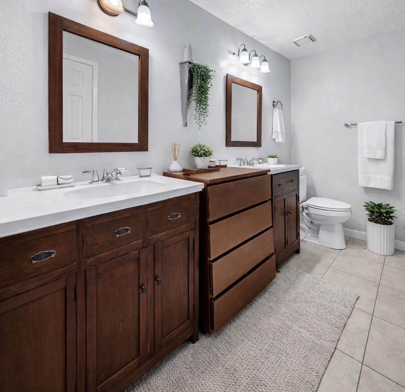 Bathroom with two dark wood vanities, white countertops, and framed mirrors.