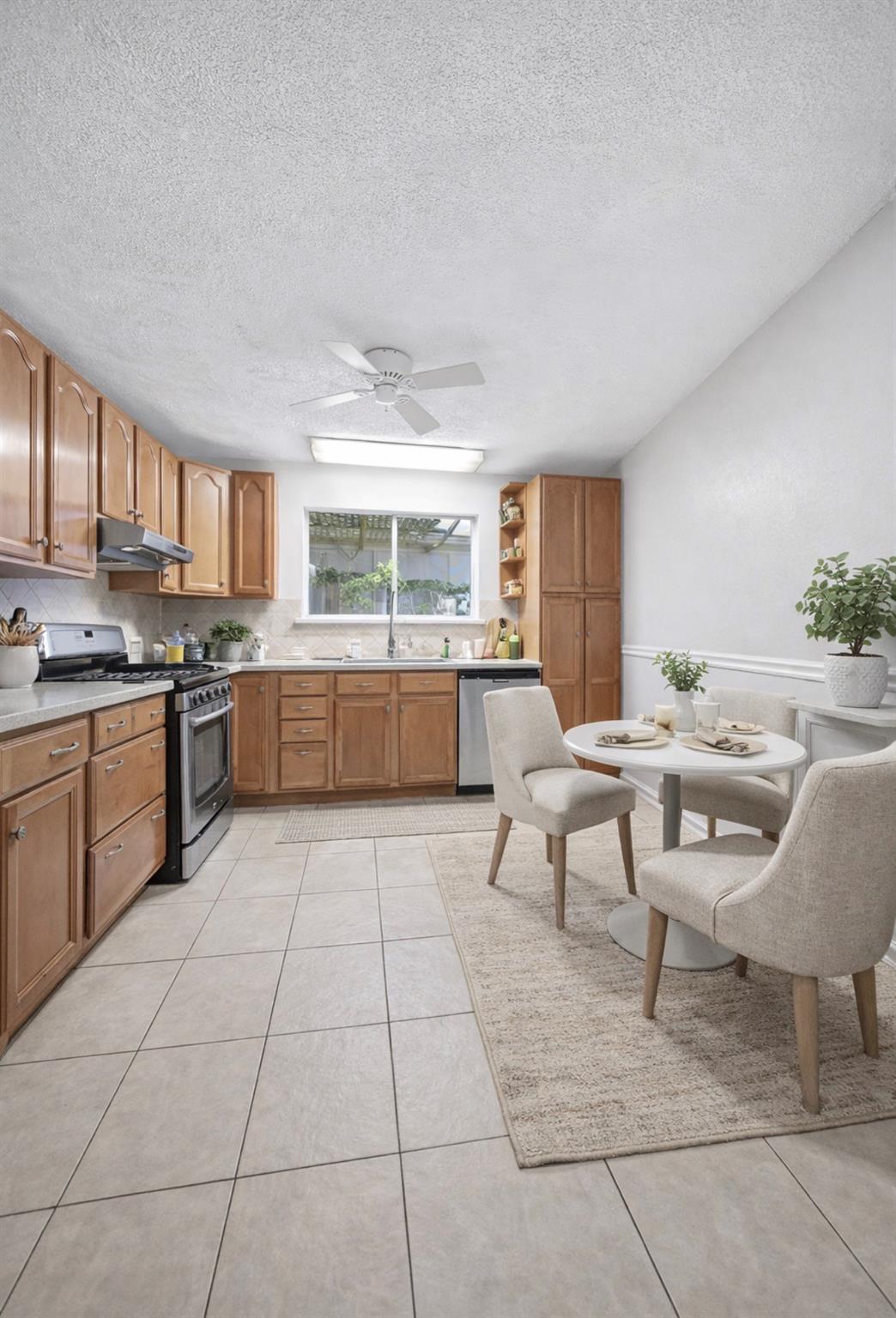 Kitchen with warm wood cabinets, stainless-steel range, and a round dining table by the window.