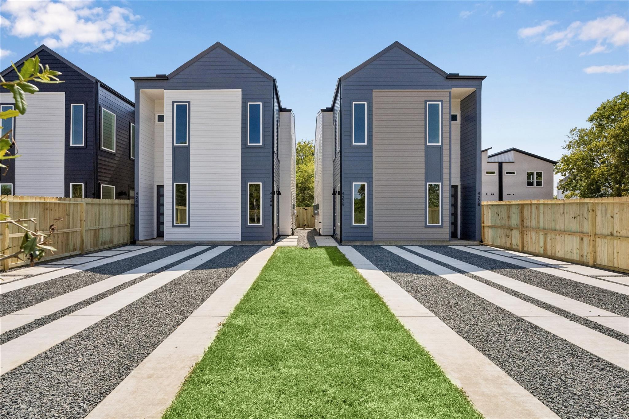 Two modern gray-and-white townhomes with separate striped gravel-and-concrete driveways.
