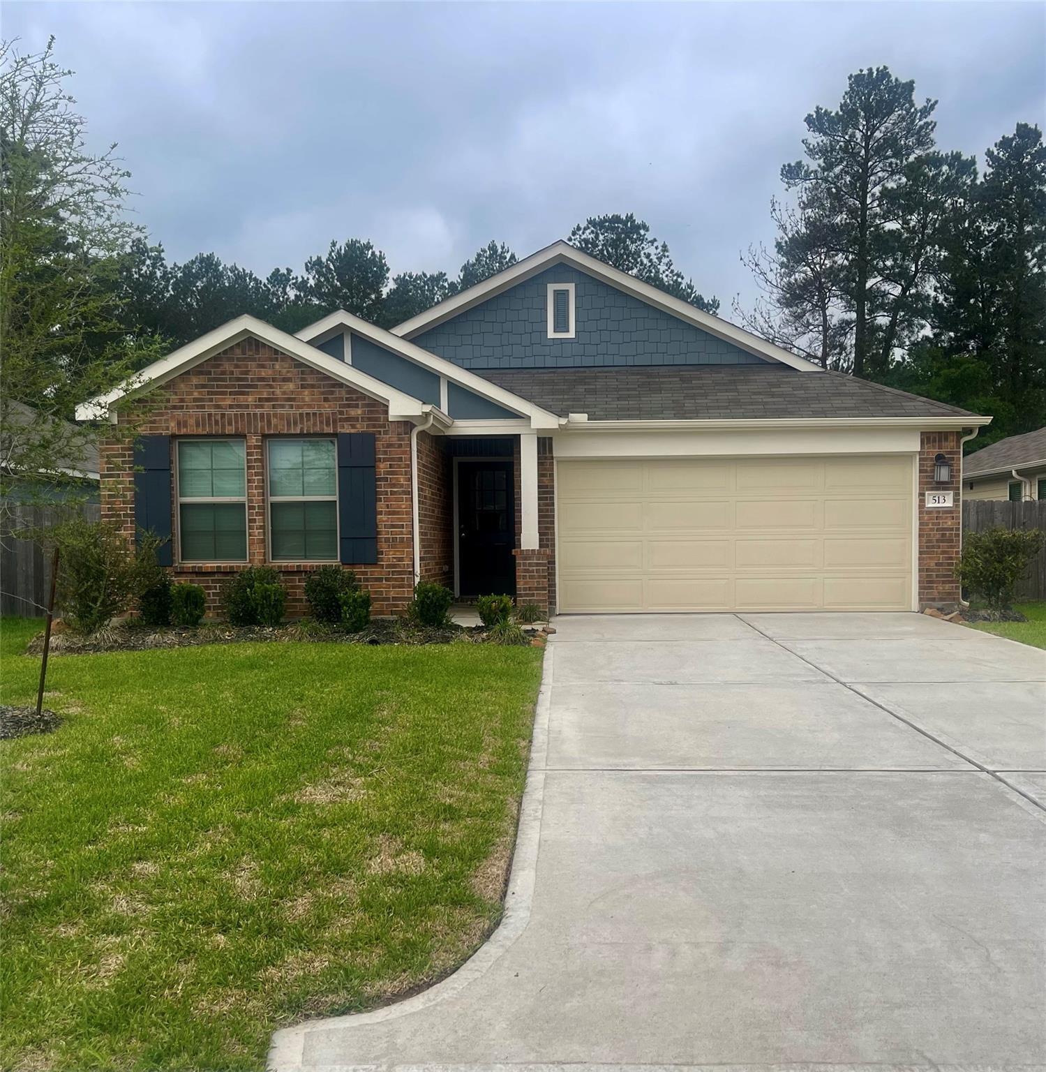 Brick house with blue siding, a two-car garage, and a wide concrete driveway.