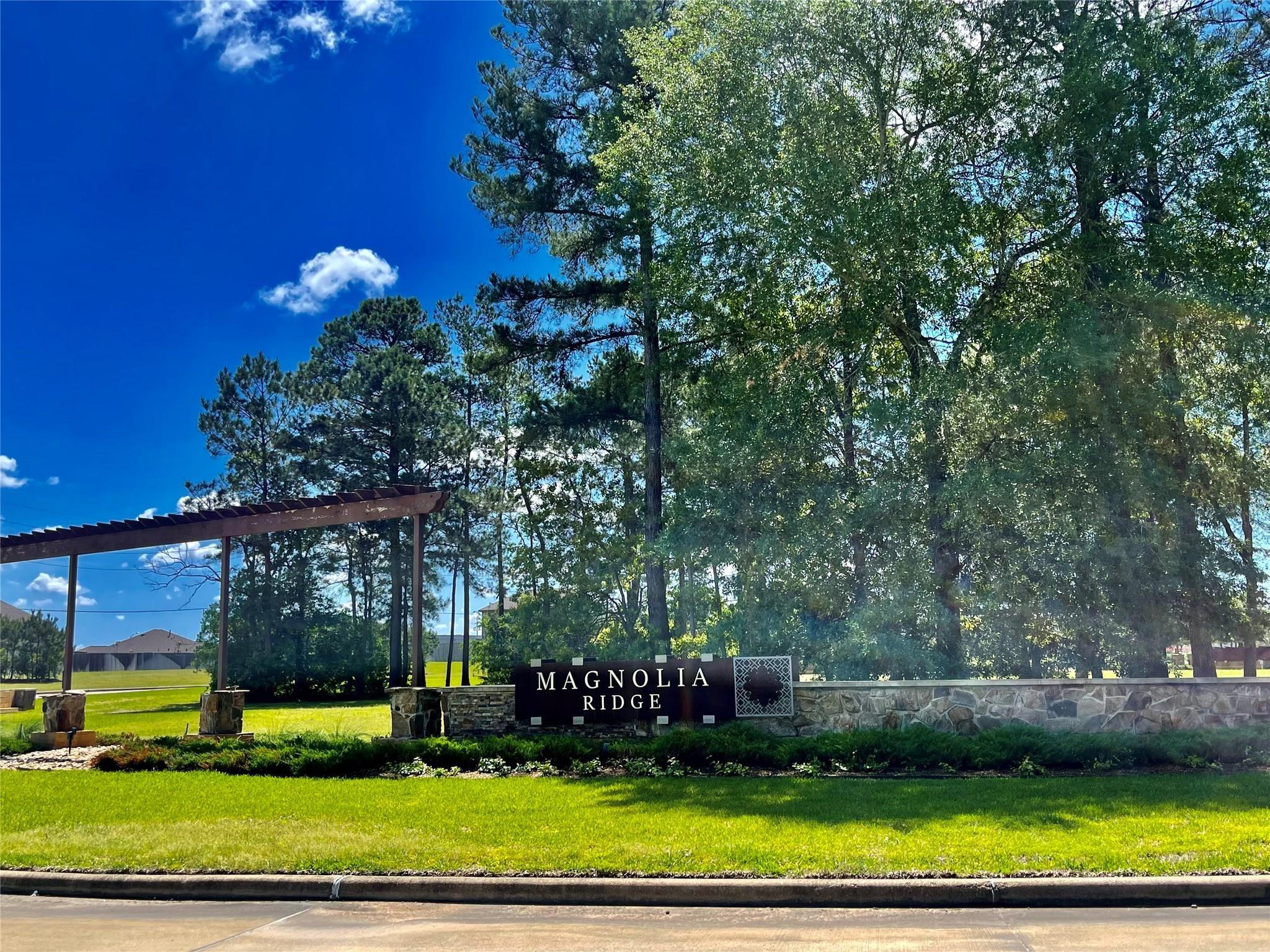 Magnolia Ridge community entrance with a stone sign wall and wooden pergola.