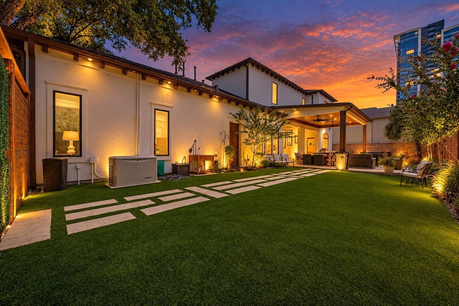 Rear patio and lawn with outdoor seating beneath a vivid sunset sky.