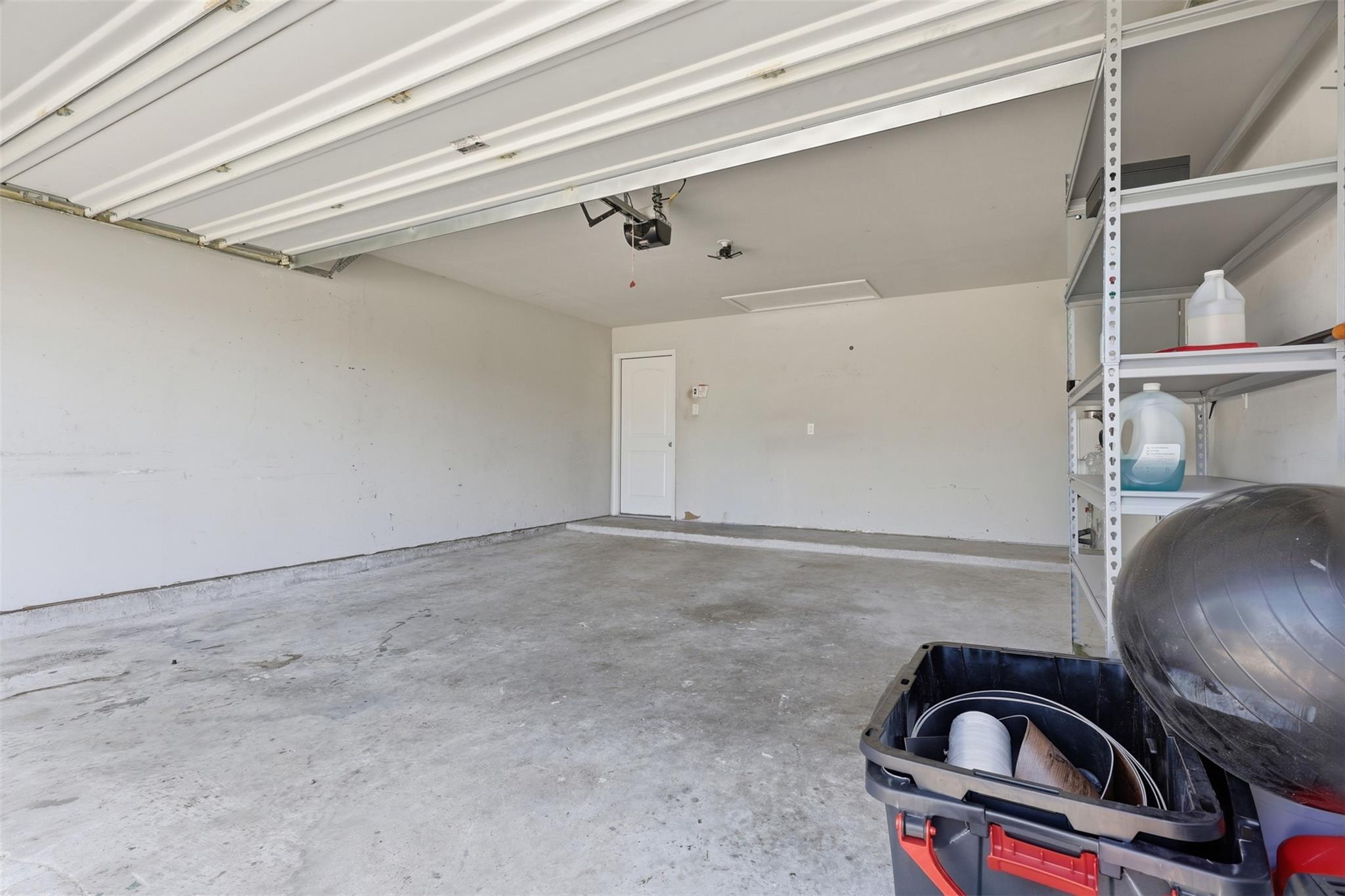 Spacious garage with a raised overhead door and metal storage shelves along one side.