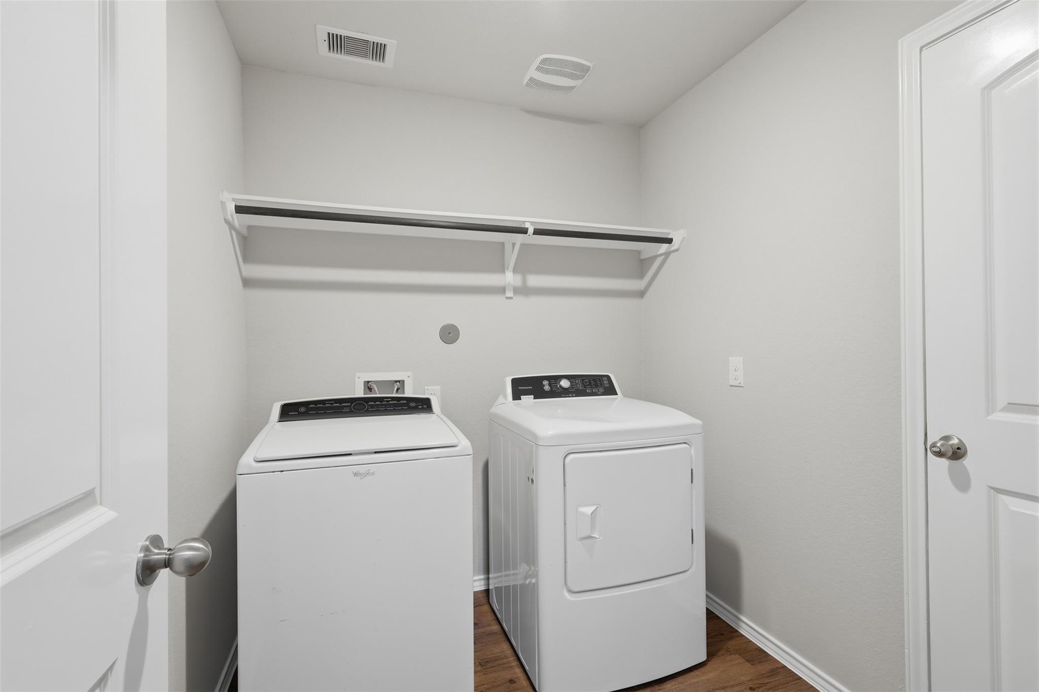 Laundry room with a washer and dryer beneath a wall-mounted shelf.