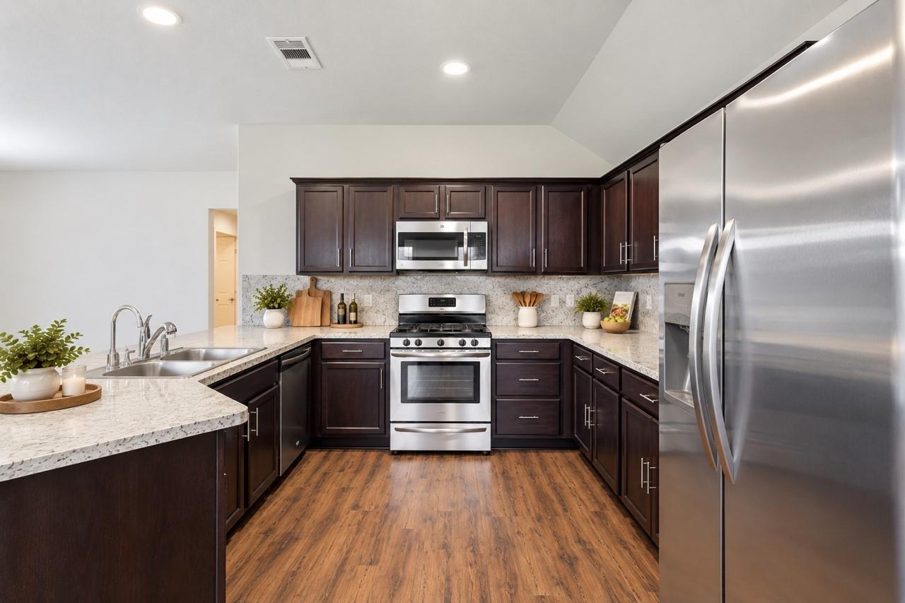 Kitchen with dark wood cabinets, stainless steel appliances, and a large island with a double-basin sink.
