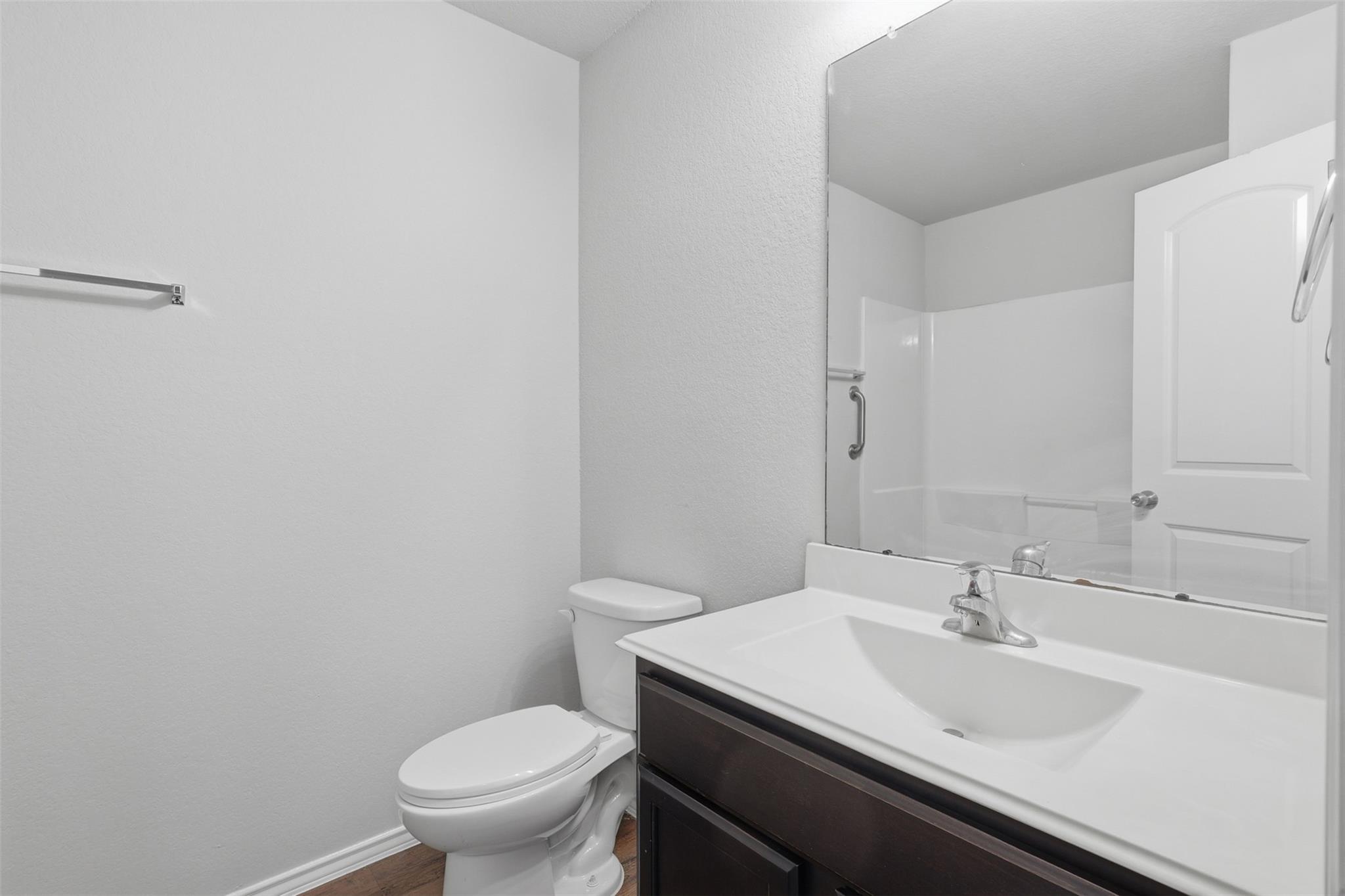 Bathroom with a dark wood vanity, white sink, large mirror, and toilet.