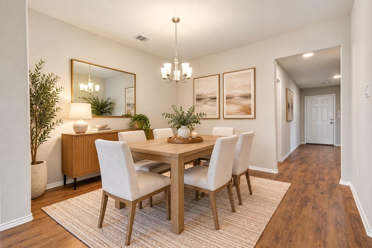 Staged dining room with a wood table, upholstered chairs, and a slatted sideboard beside the entry hall.