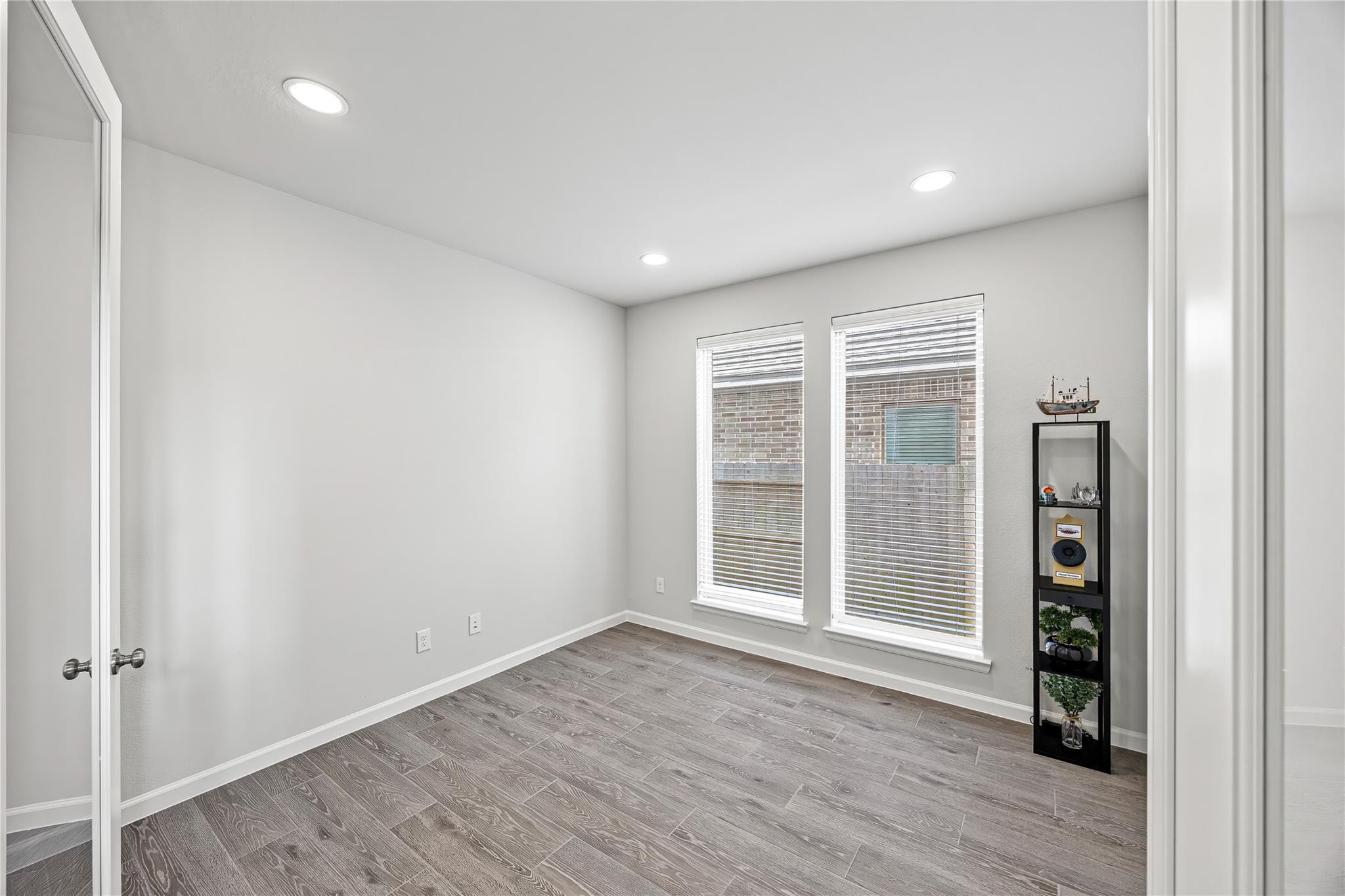 Unfurnished room with gray tile flooring, two blind-covered windows, and a narrow display shelf.