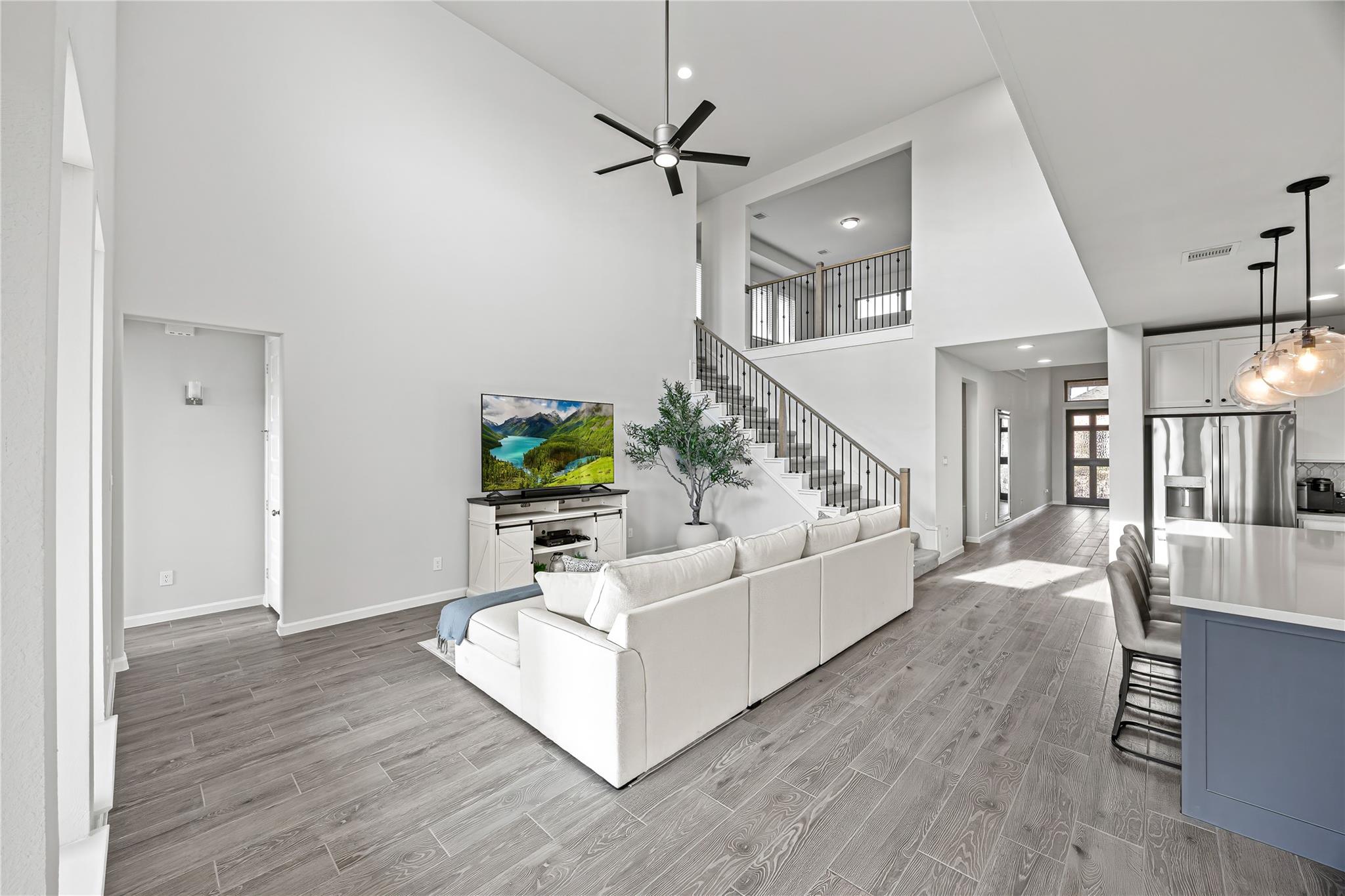 Open-plan living room with a white sectional, staircase, and kitchen island.