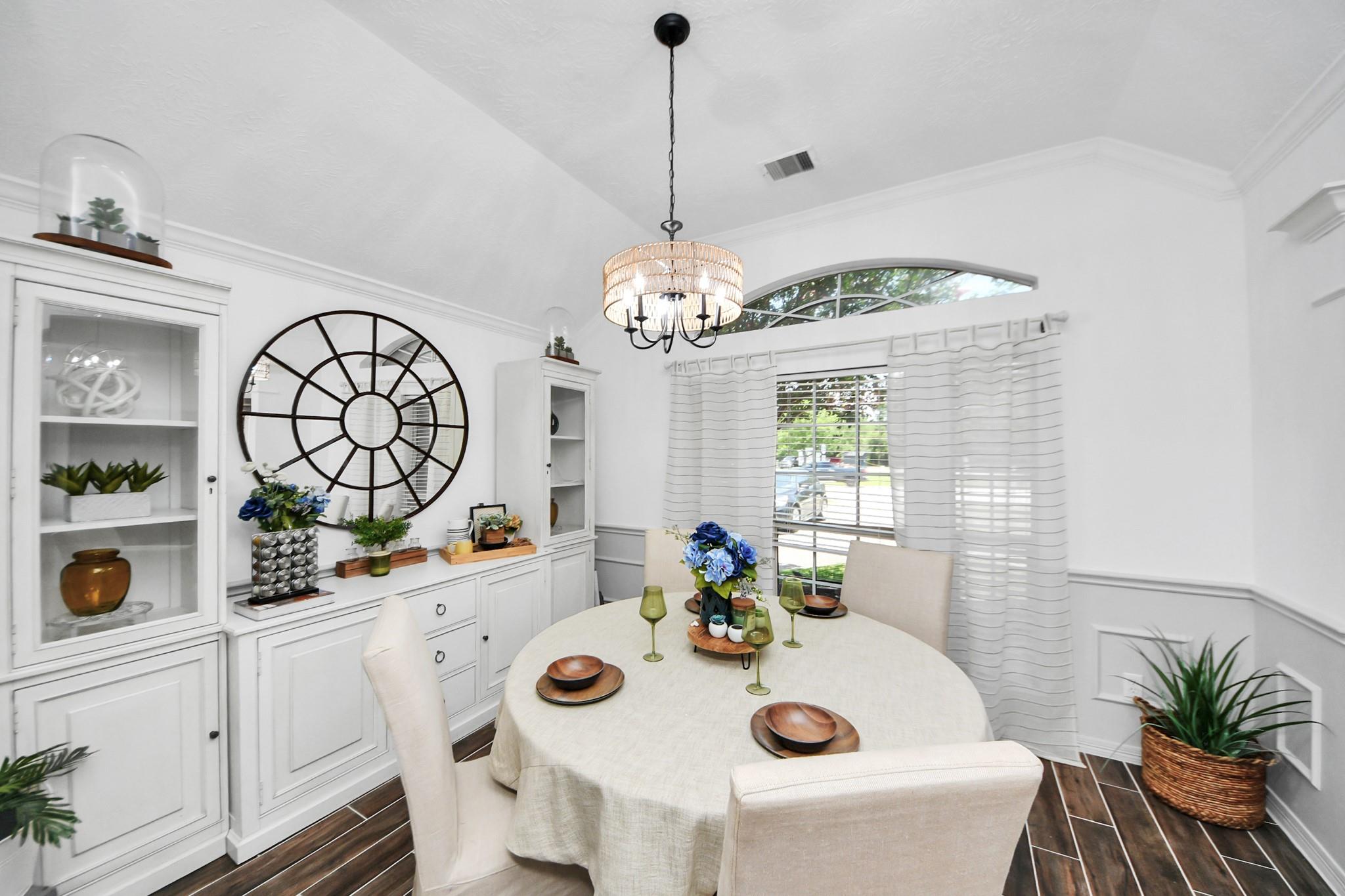 Staged dining room with white built-ins, a large circular mirror, and a chandelier over a round table.