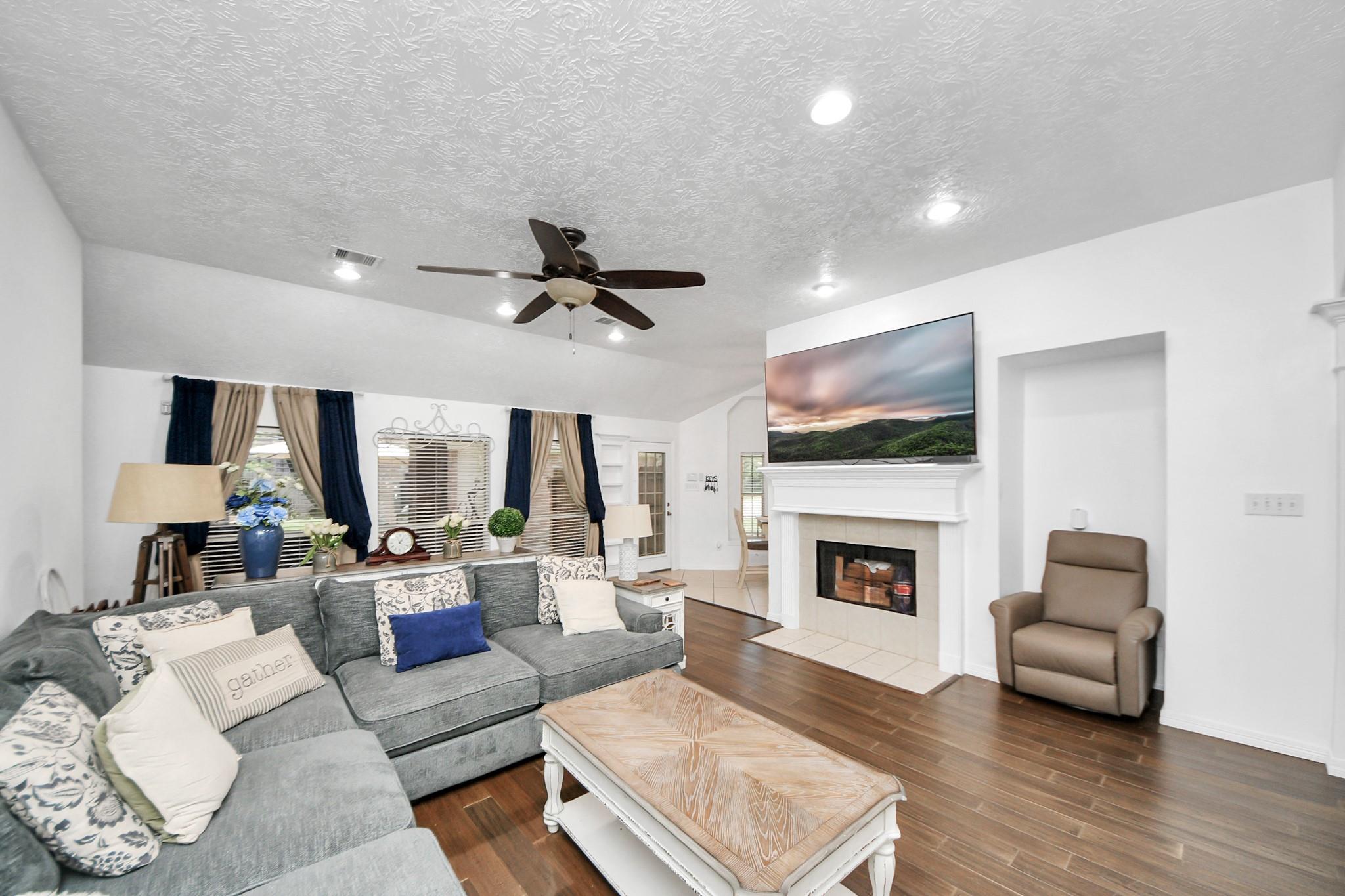 Furnished living room with a gray sectional, wood coffee table, and fireplace beneath a television.