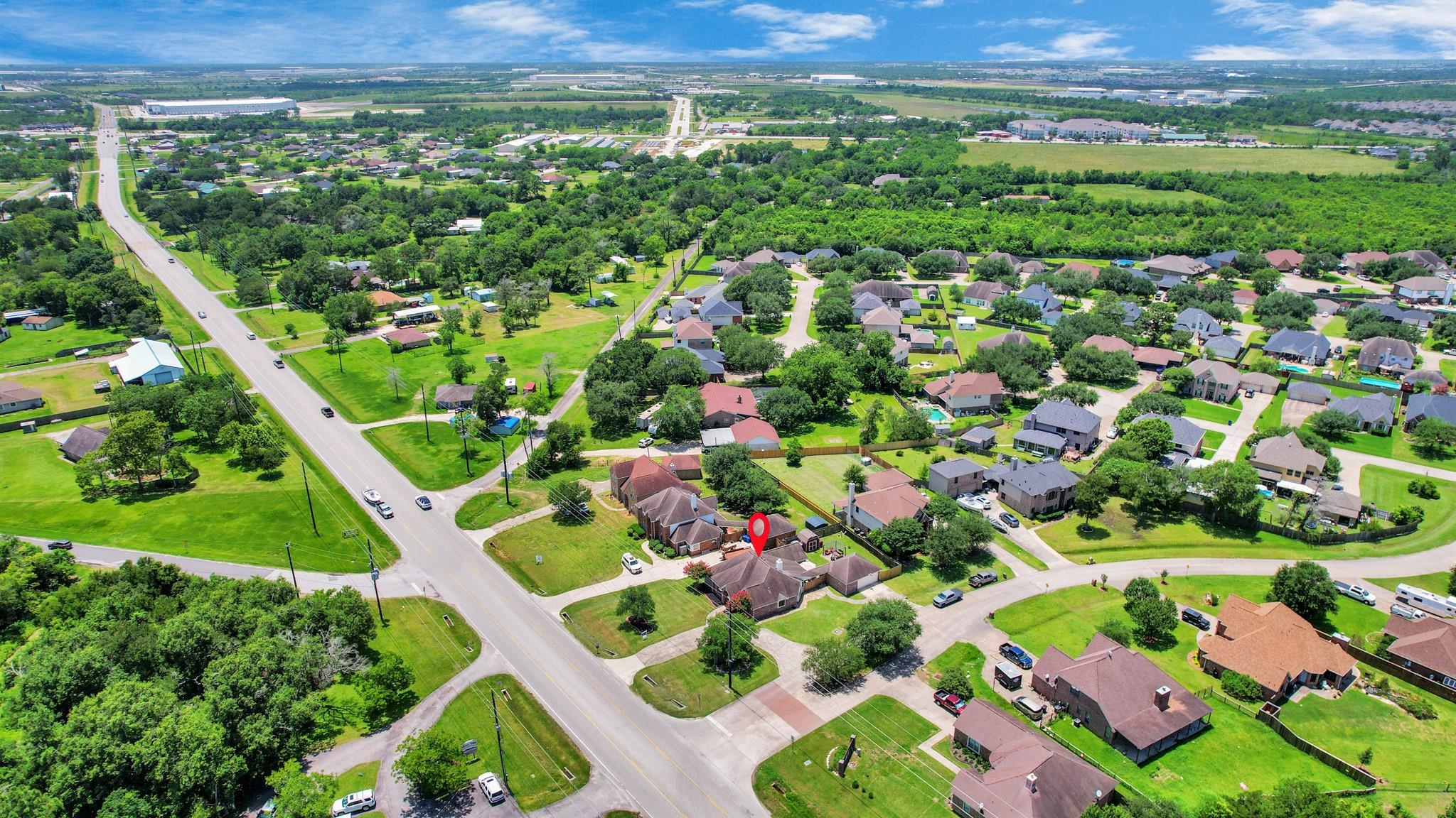 Aerial view of the marked home amid a tree-lined neighborhood and surrounding roads.