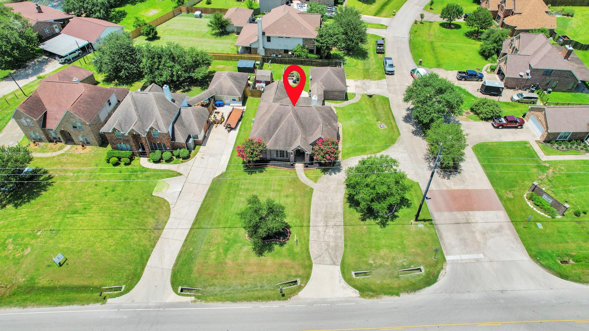 Aerial view of a brick house marked by a red location pin among neighboring homes.