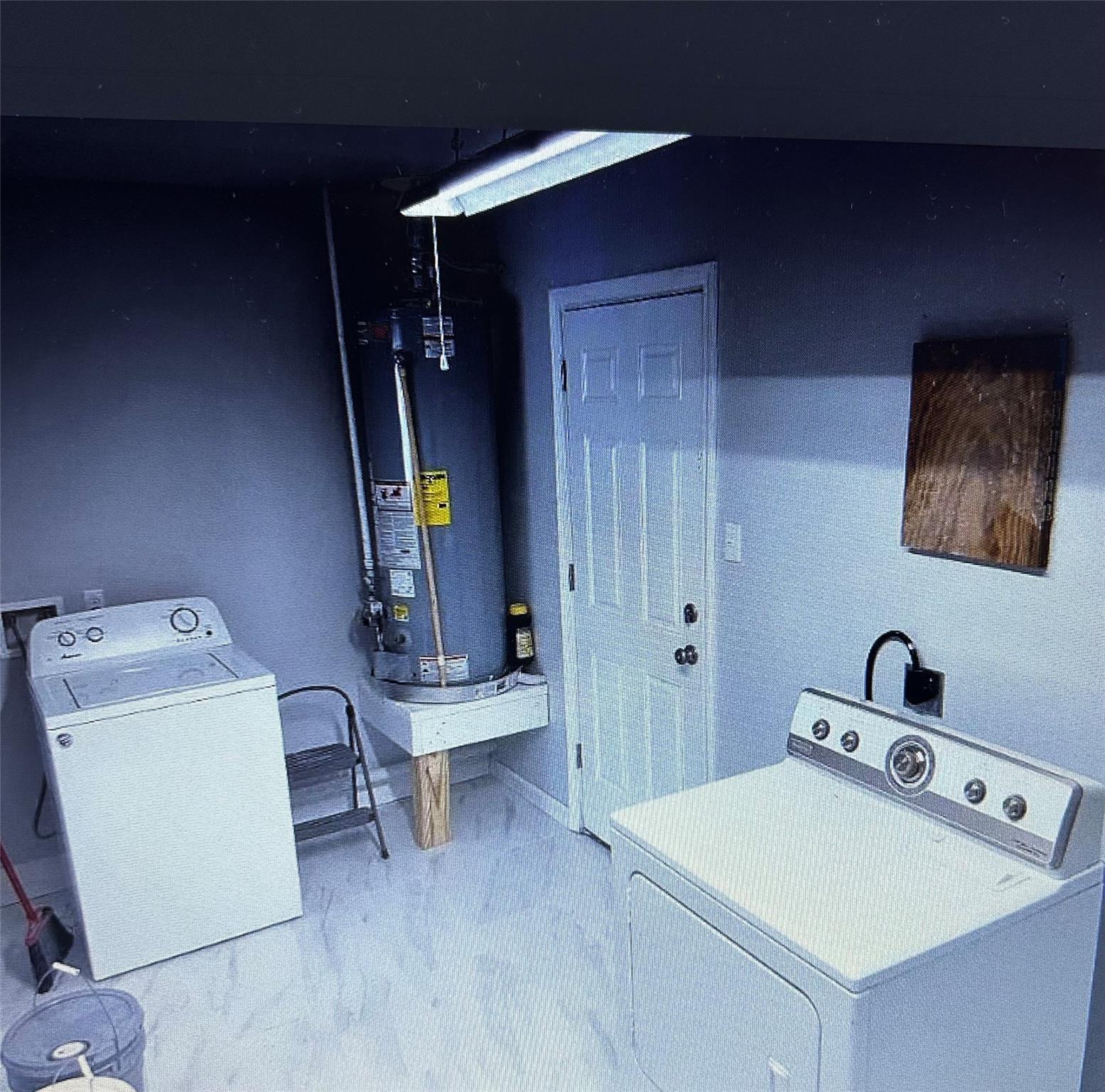 Laundry room with a top-loading washer and dryer beside a water heater.
