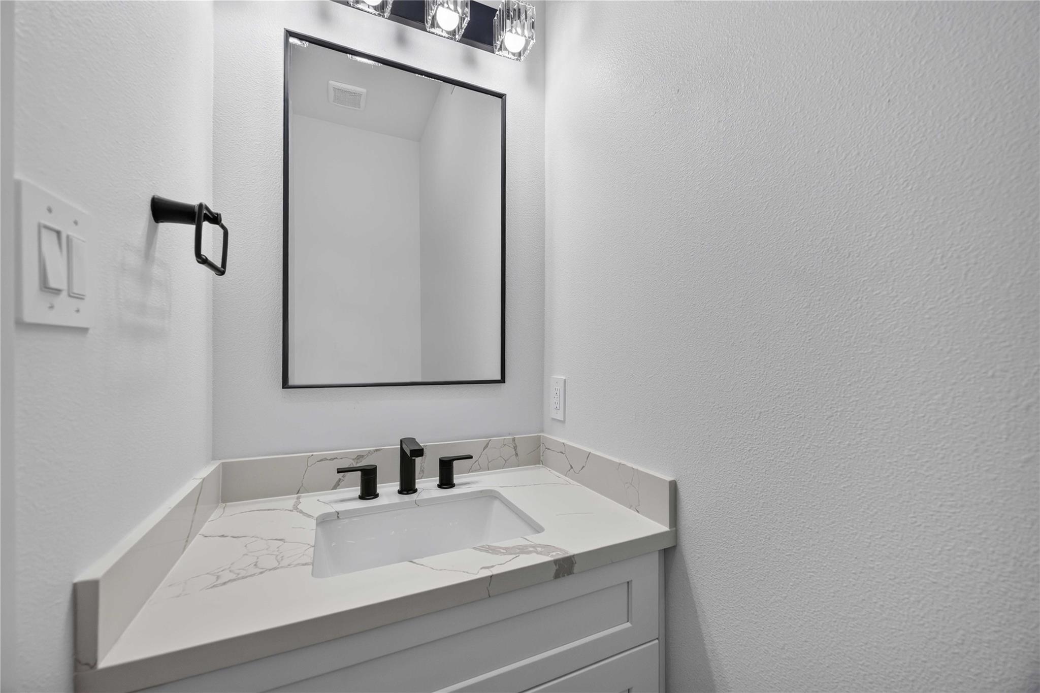 Bathroom vanity with a marble-look counter, undermount sink, and matte black faucet.