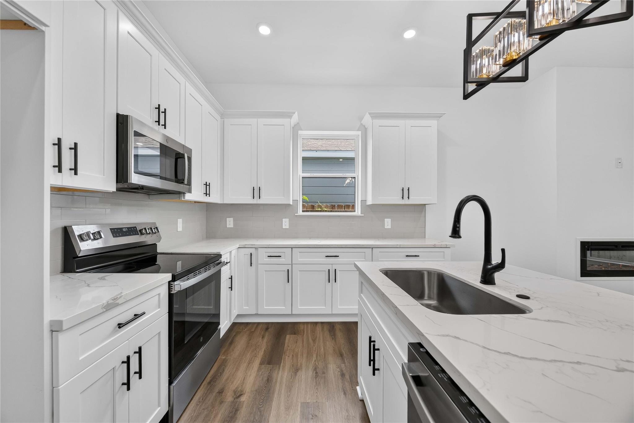 Kitchen with white shaker cabinets, marble-look island countertop, and black faucet.