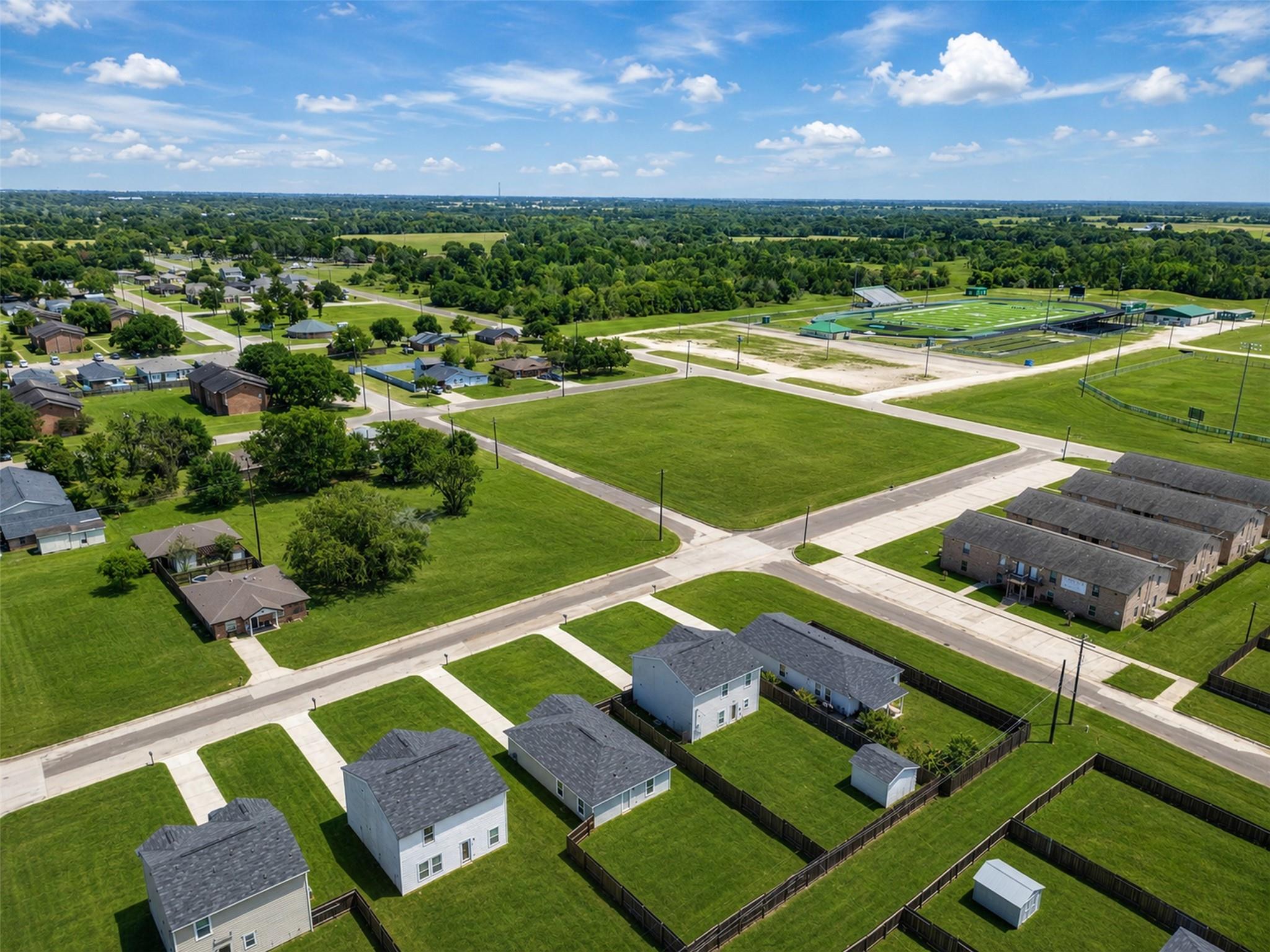Aerial view of a residential neighborhood with fenced yards and a sports complex nearby.