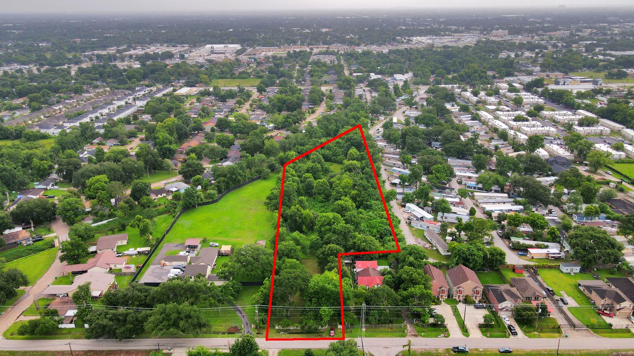 Wooded land parcel outlined in red among surrounding homes and streets.
