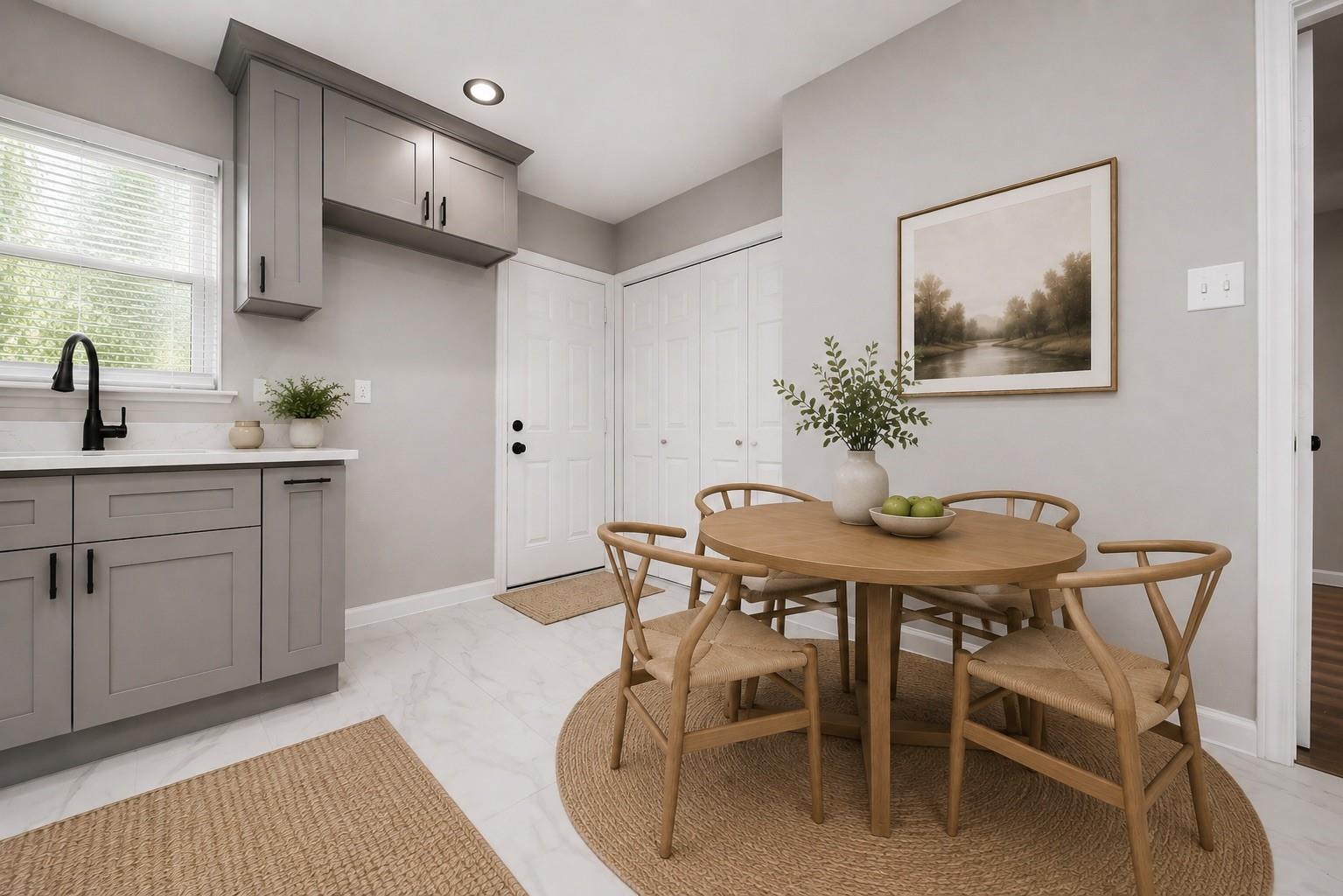 Kitchen and dining nook with gray cabinets, a round wooden table, and woven chairs.