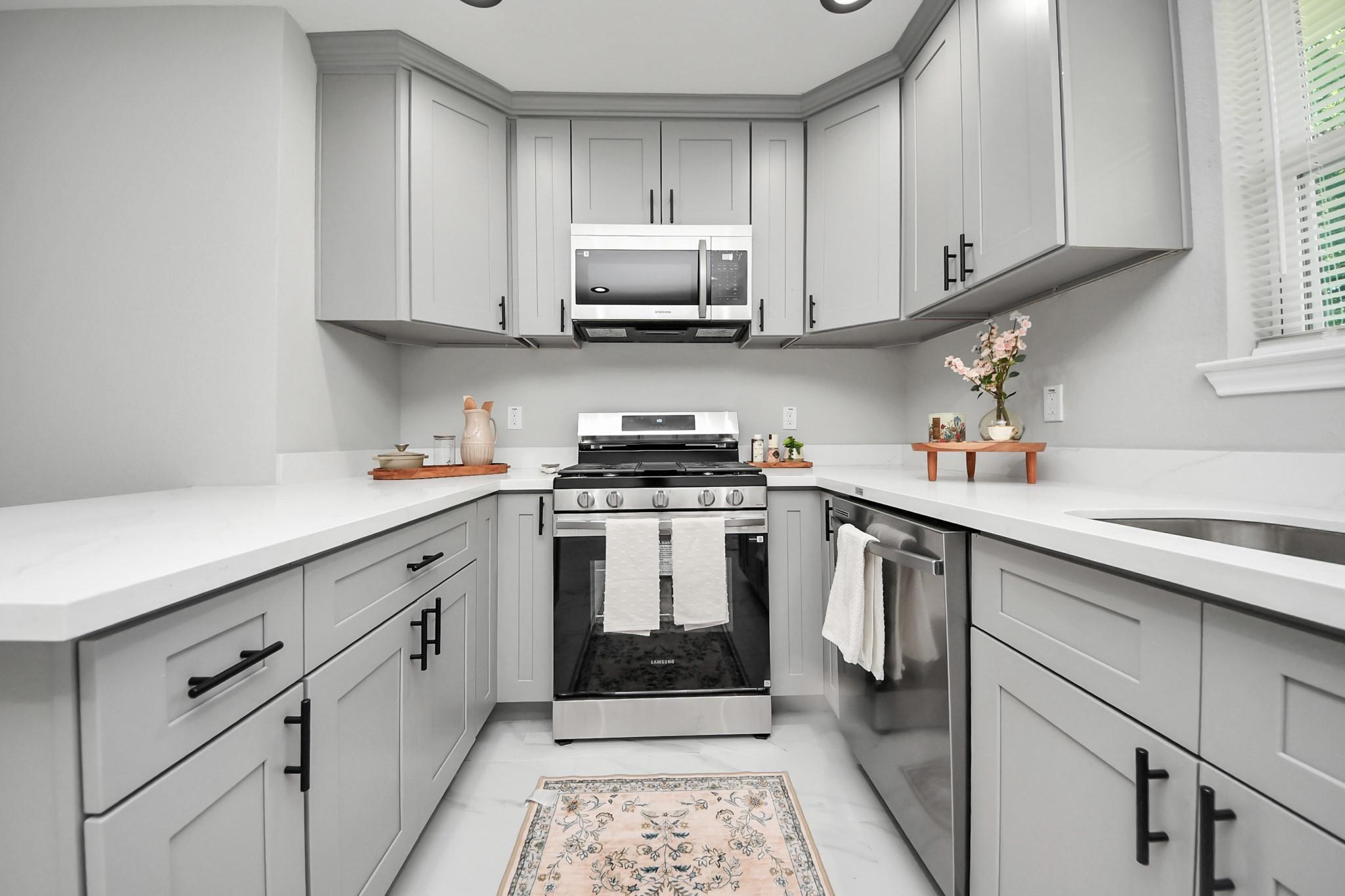 Bright kitchen with white cabinets, stainless steel appliances, and a patterned runner.