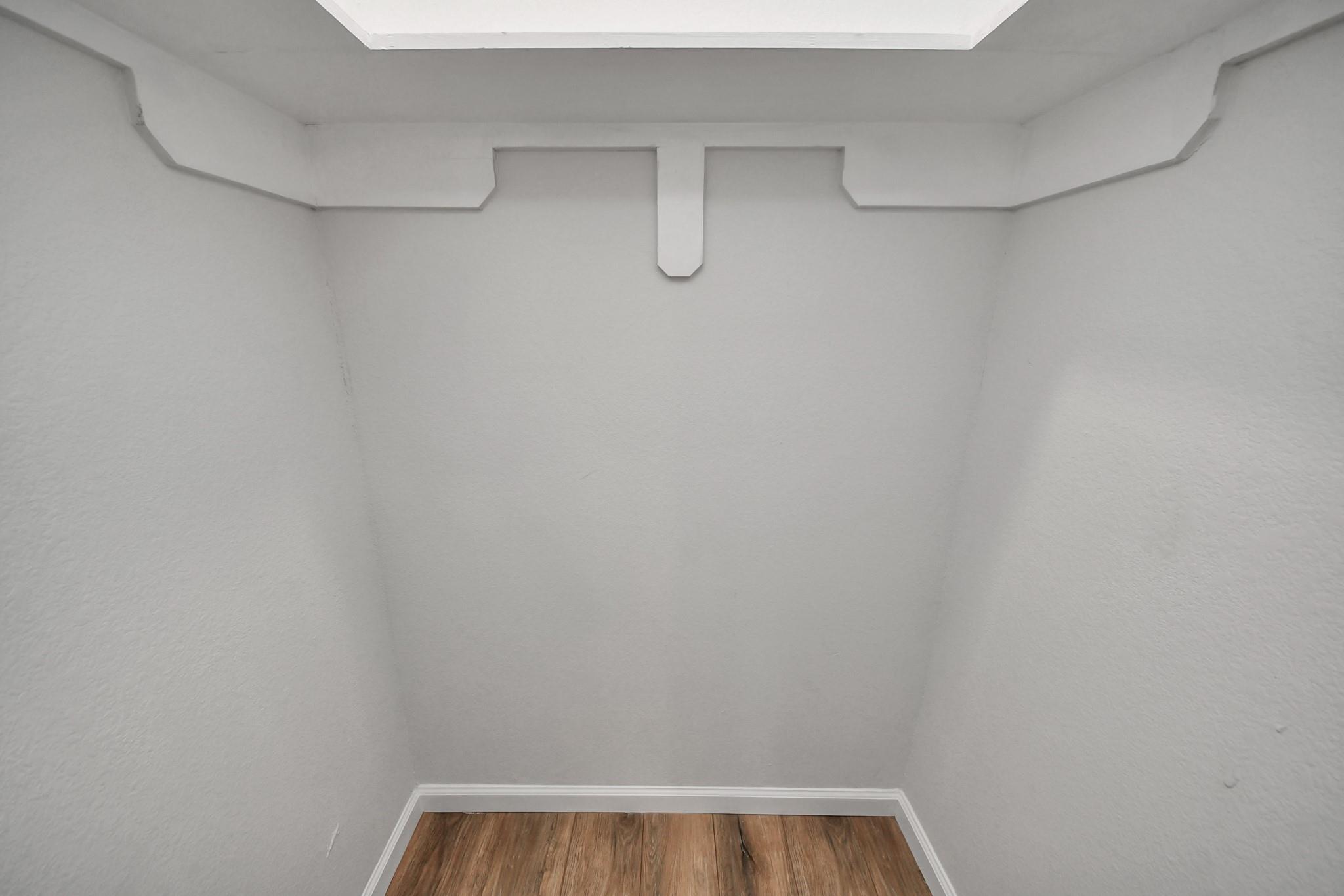 Empty recessed nook with gray walls, decorative white ceiling trim, and wood-look flooring.