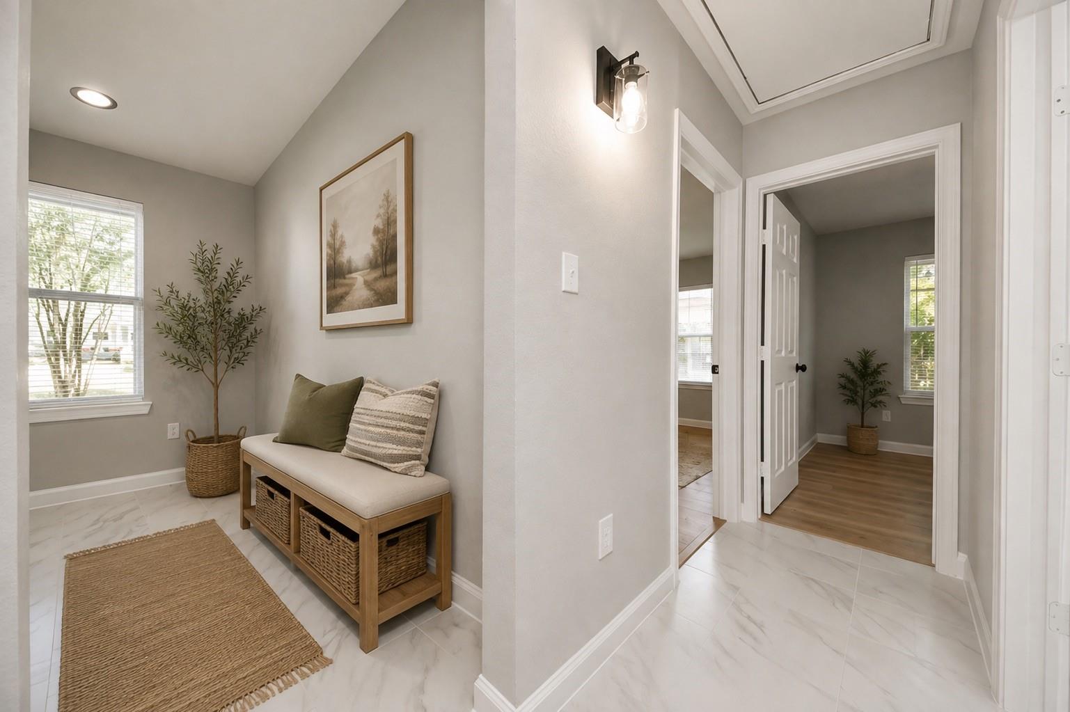 Staged entryway with a cushioned bench, woven baskets, and marble-look tile floor.