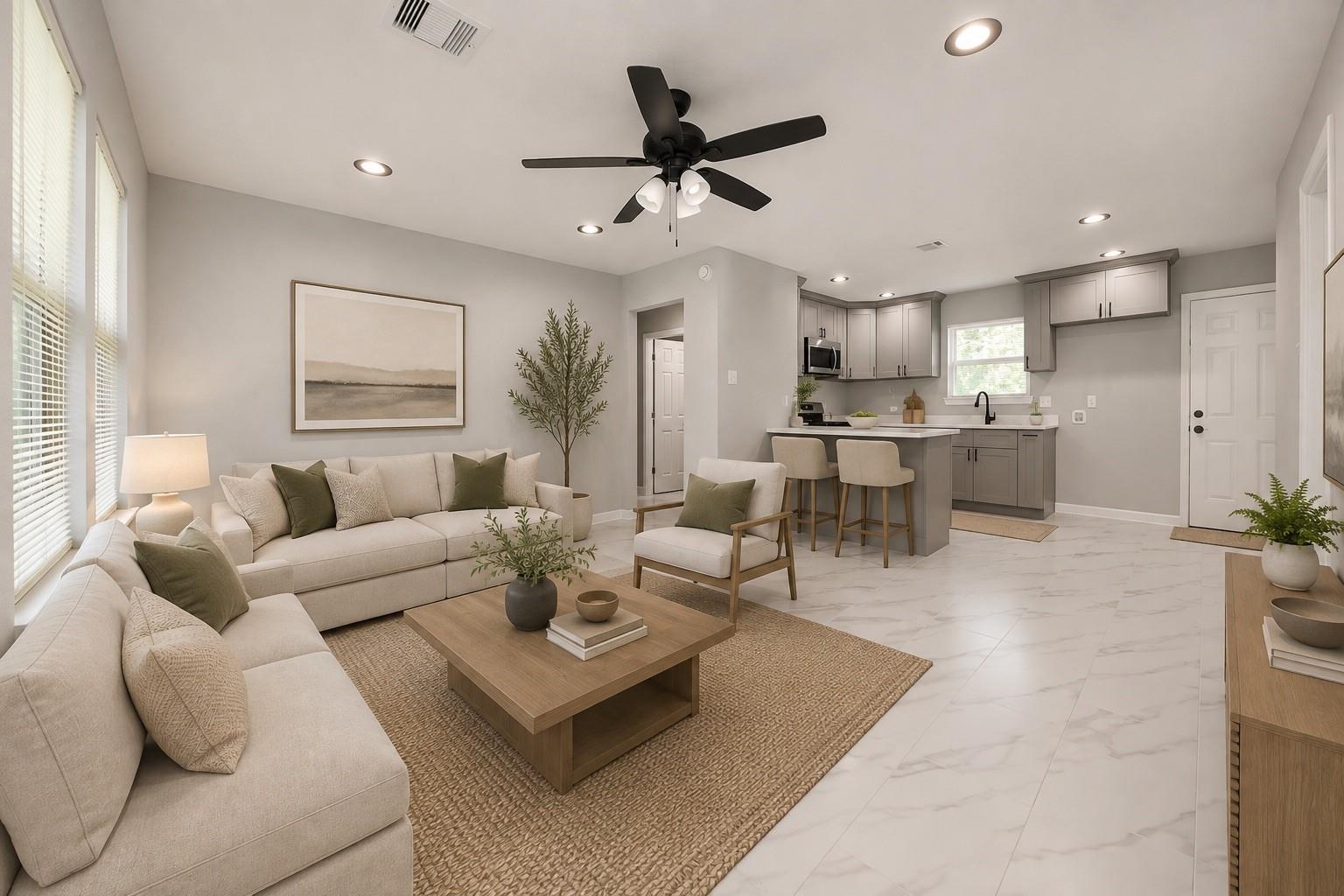 Open-plan living room and kitchen with cream sofas, a wood coffee table, and gray cabinets.