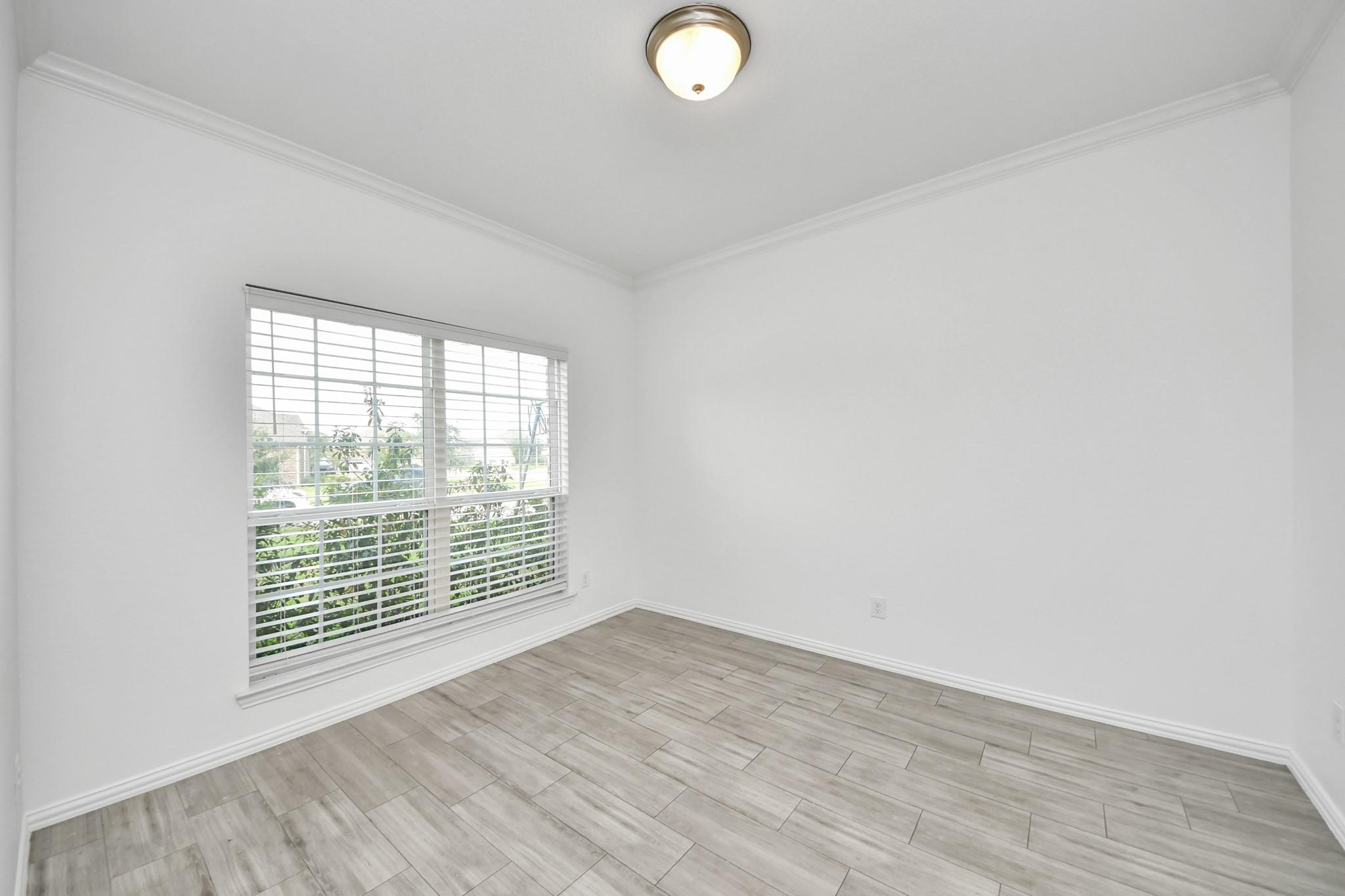 Vacant room with gray tile flooring and a large window with white blinds.