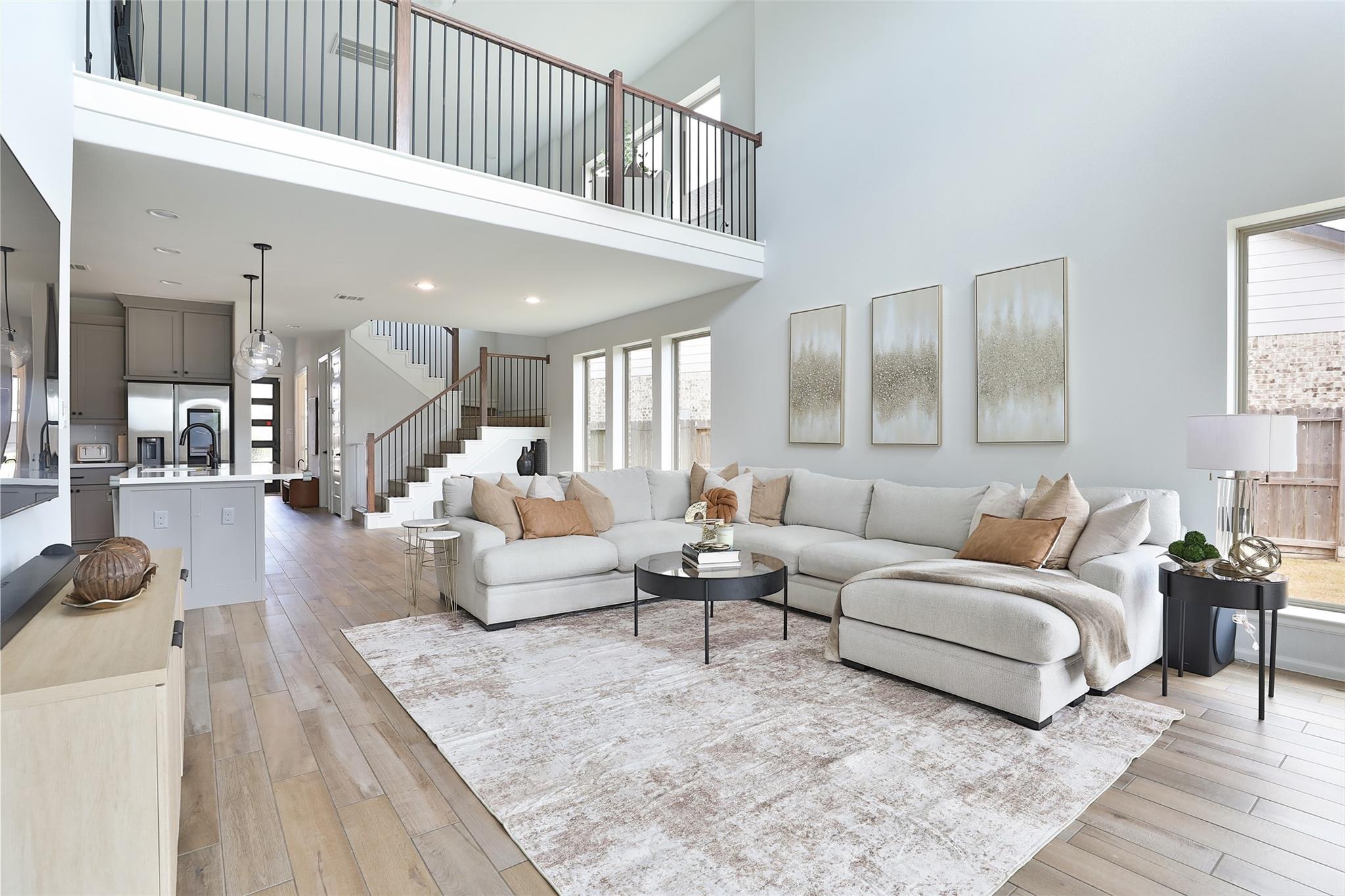Open-plan living room with a white sectional, gray kitchen, and upstairs mezzanine.