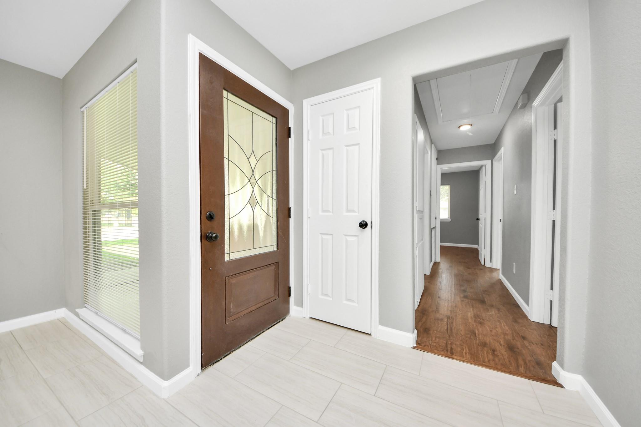 Entry foyer with decorative glass front door and hallway with wood flooring.