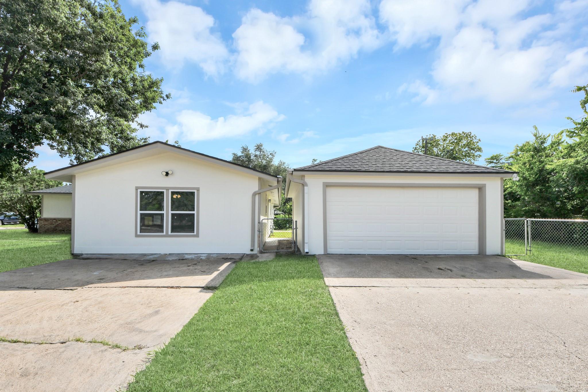 Single-story white house with attached two-car garage, broad driveway, and lawn.