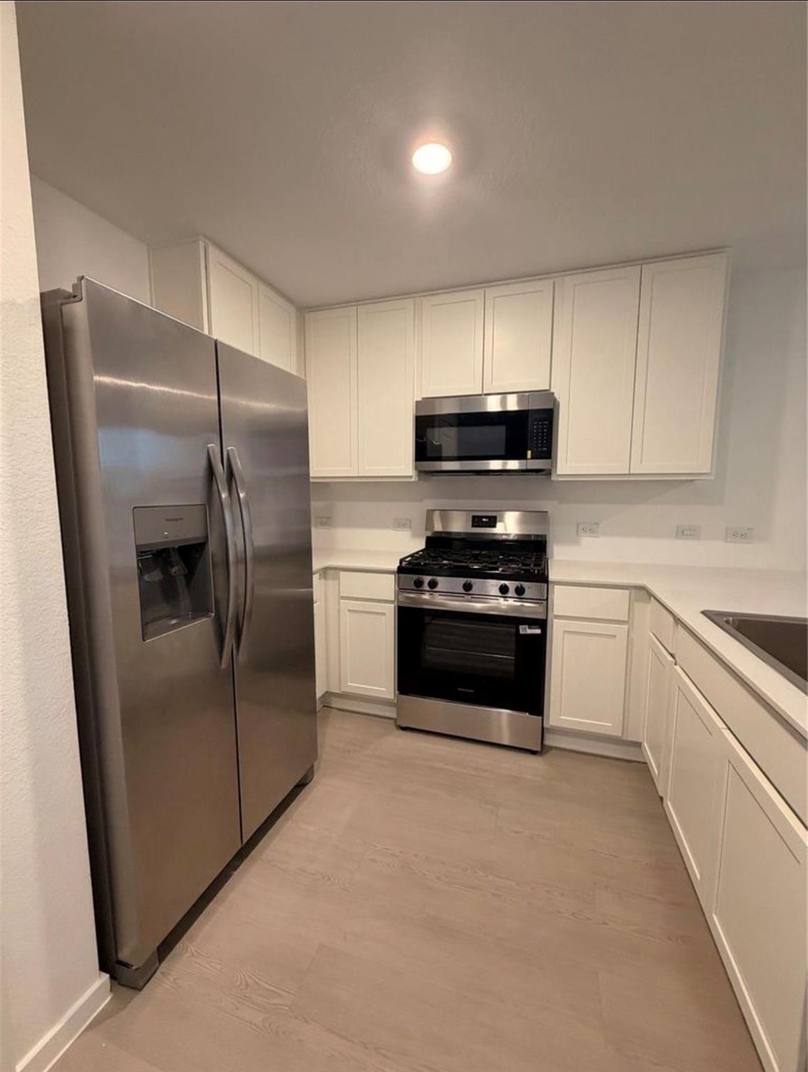 Kitchen with white cabinets, stainless steel appliances, and a gas range.
