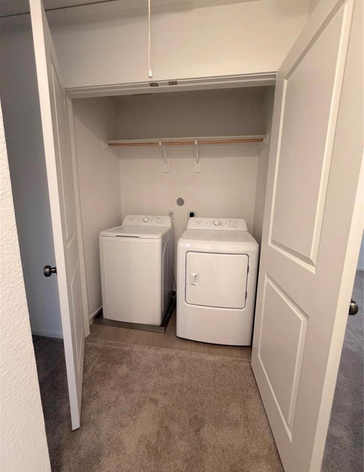 Laundry closet with a top-loading washer, front-loading dryer, and hanging rod.