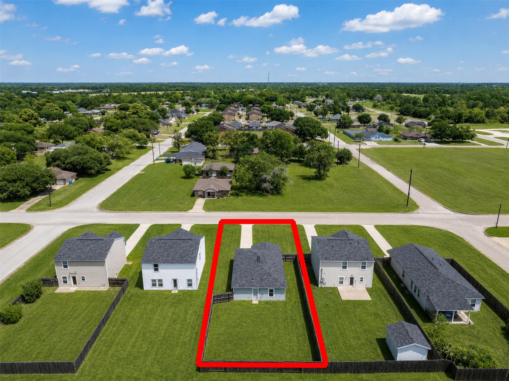 Aerial view of a single-story house and fenced lot outlined in red, surrounded by neighborhood homes.