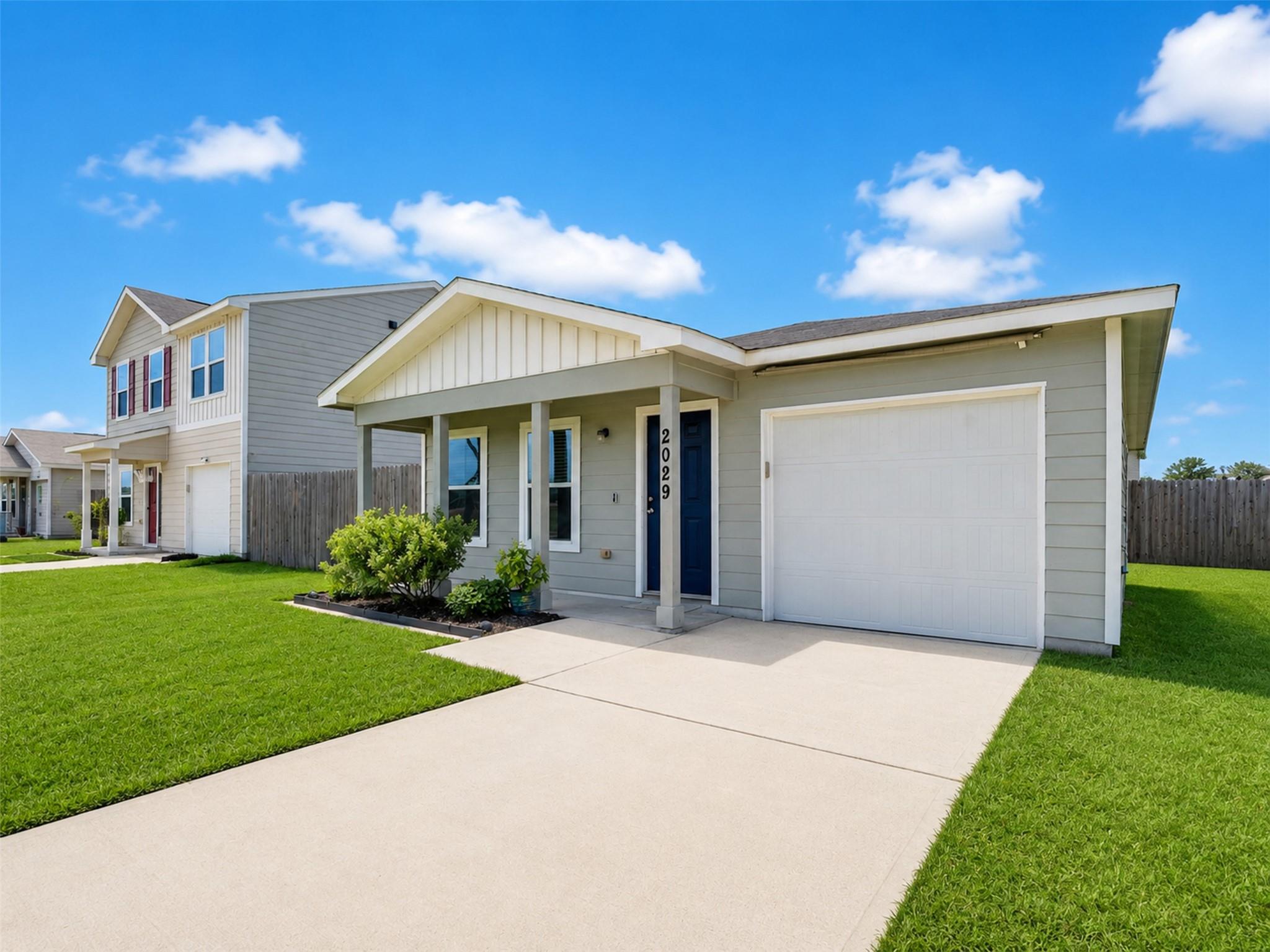 Light gray home with a covered porch, blue front door, and attached garage.