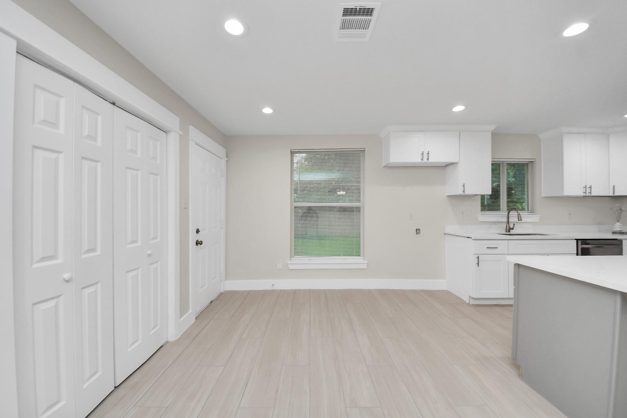 Vacant kitchen with white cabinets, a peninsula island, and light wood-look flooring.