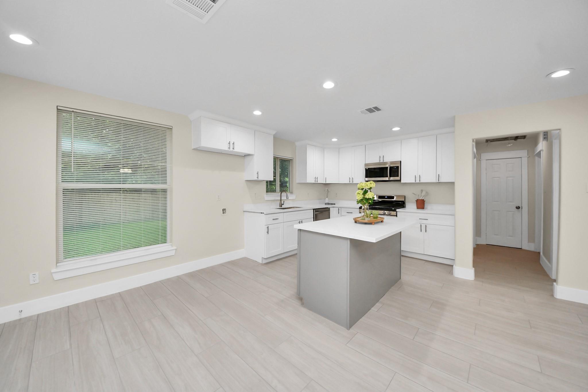 Bright kitchen with white cabinets, stainless steel appliances, and a gray island.