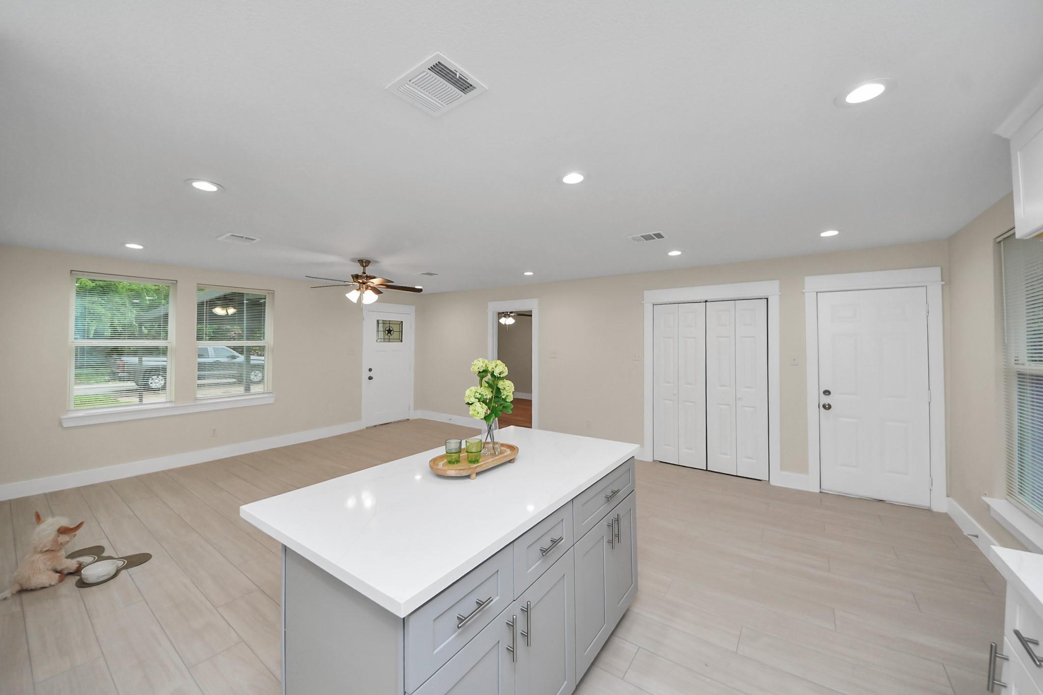 Kitchen with a large white island, gray cabinets, and a small dog beside its bowls.