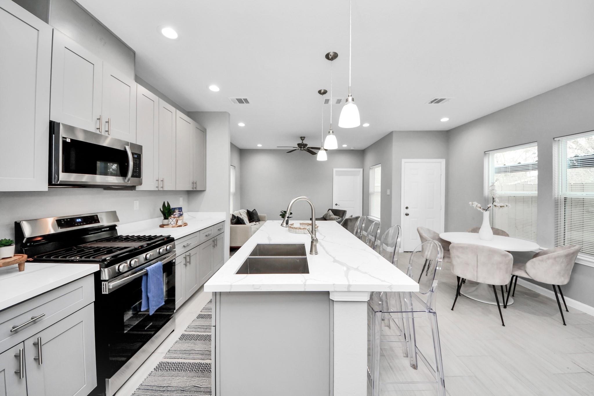 Open kitchen with a large white island, stainless steel range, and adjoining dining area.