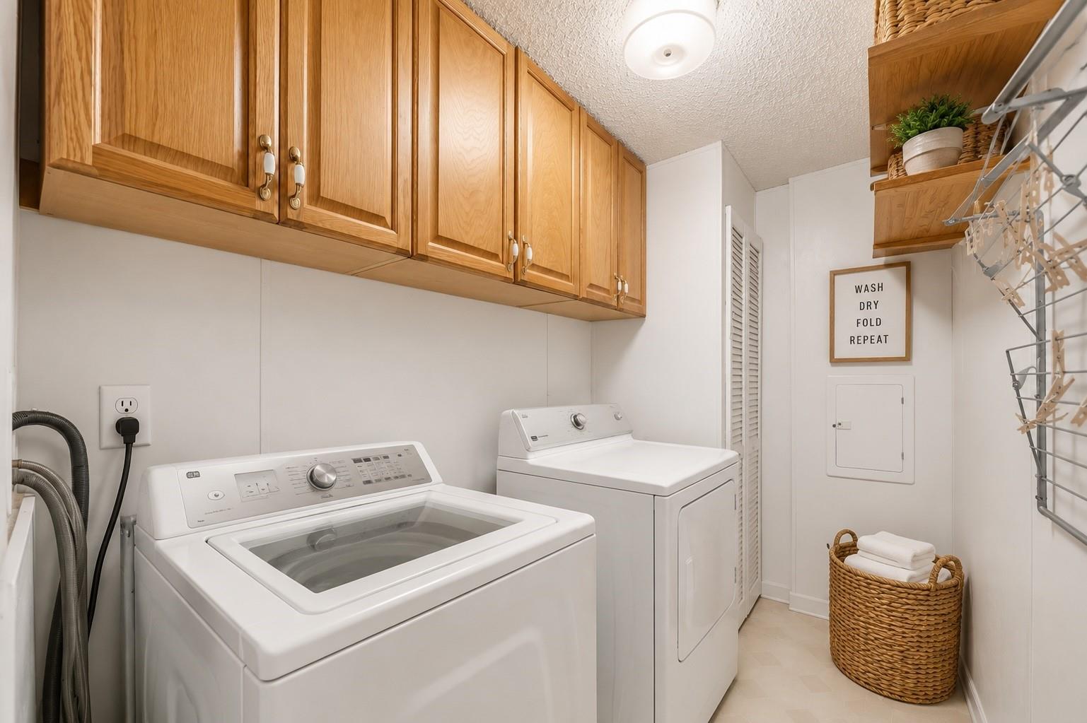 Laundry room with washer and dryer beneath wooden cabinets and a wall-mounted drying rack.