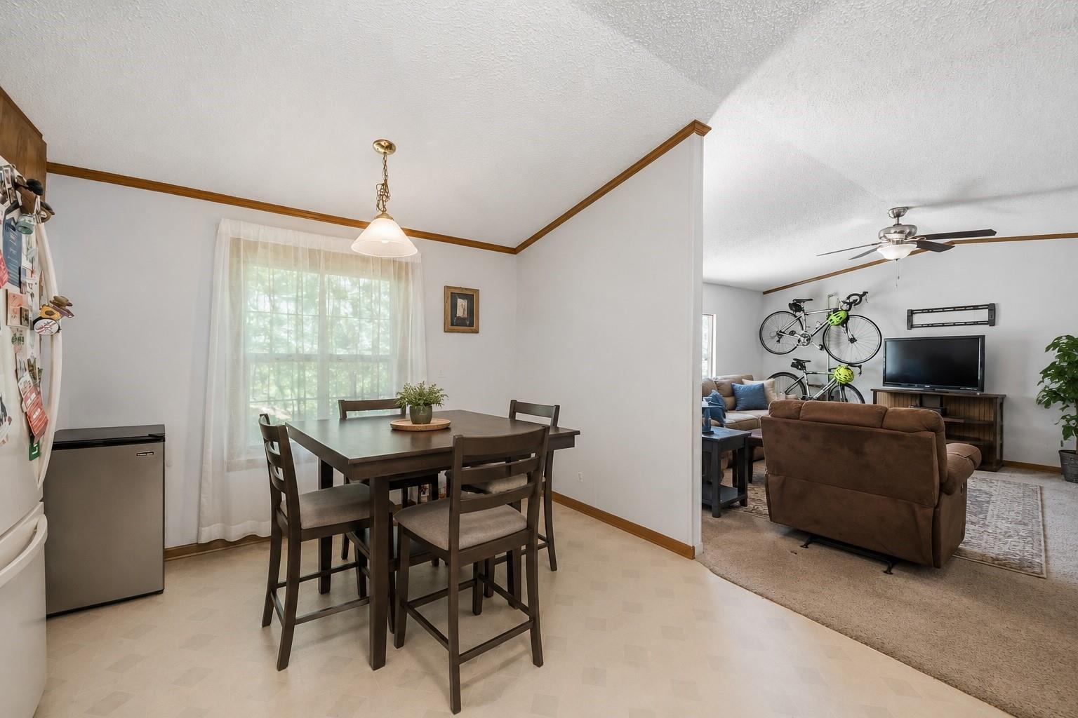 Dining area with a dark wood table opens to a living room with a brown sofa and wall-mounted bicycles.