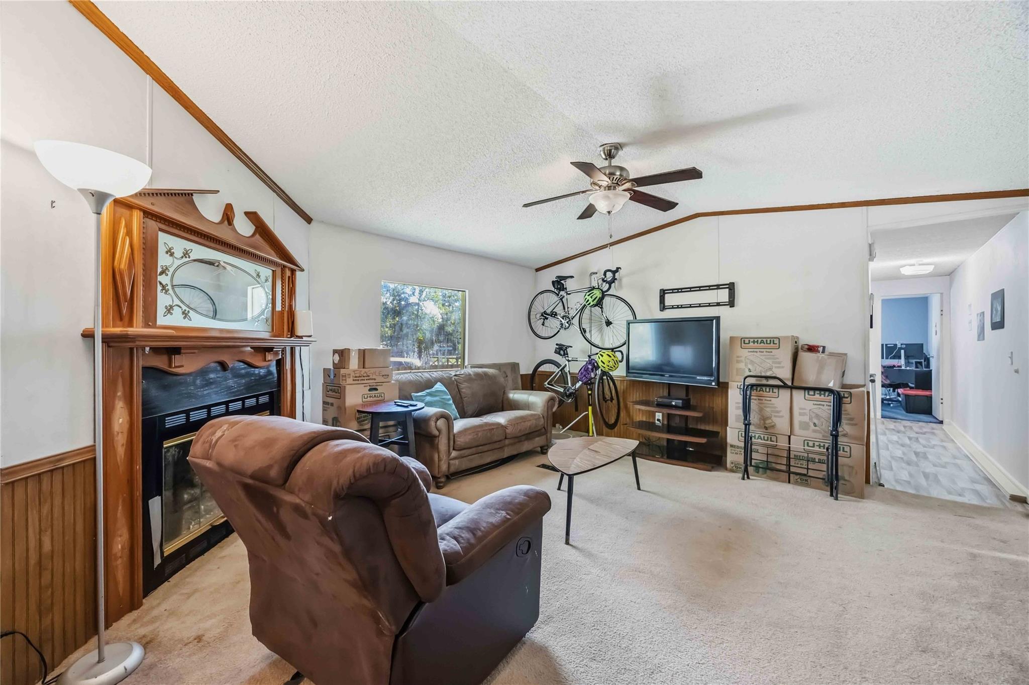 Living room with an ornate wood fireplace, wall-mounted bicycles, and moving boxes.
