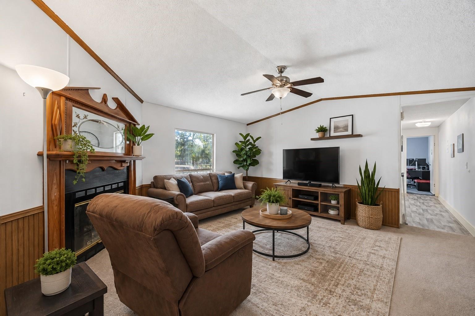Living room with a wood-trimmed fireplace, brown leather seating, and television.