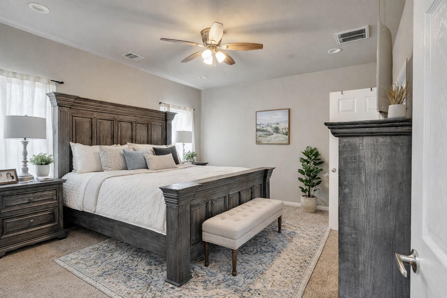 Staged bedroom with a dark paneled bed, white bedding, and a fireplace mantel.