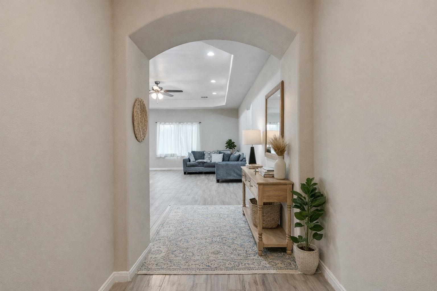 Entry hallway with an arched opening to a living room and a wooden console table.