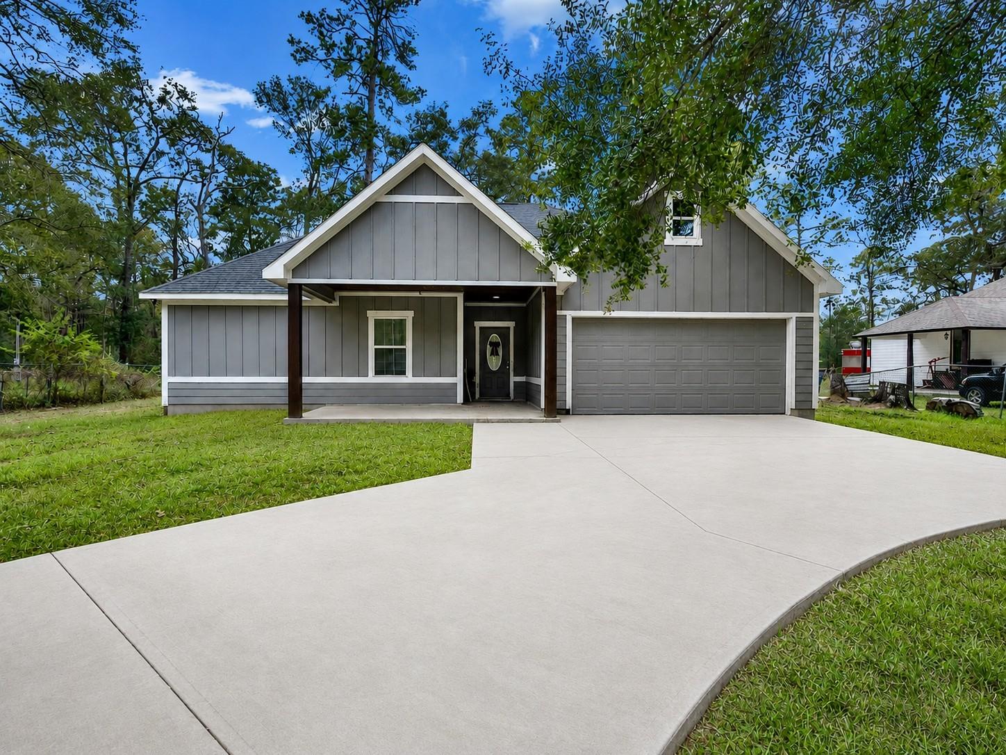 Gray house with a covered porch, attached two-car garage, and wide concrete driveway.