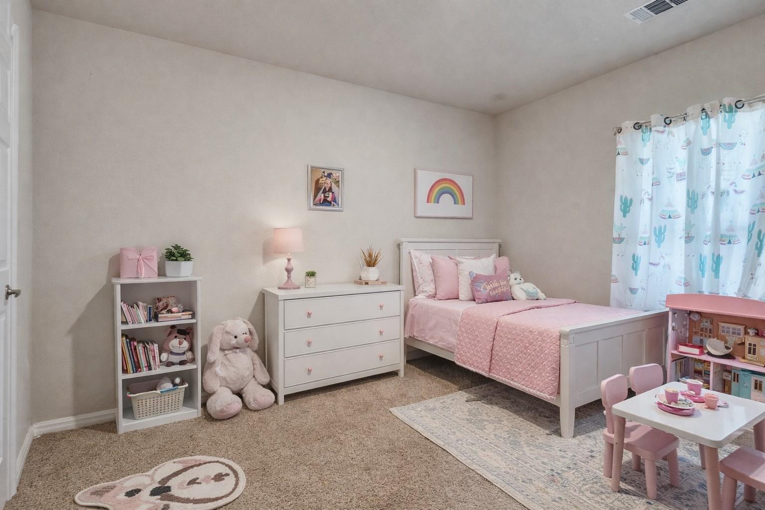 Children’s bedroom with a white bed, pink bedding, and a small play table.